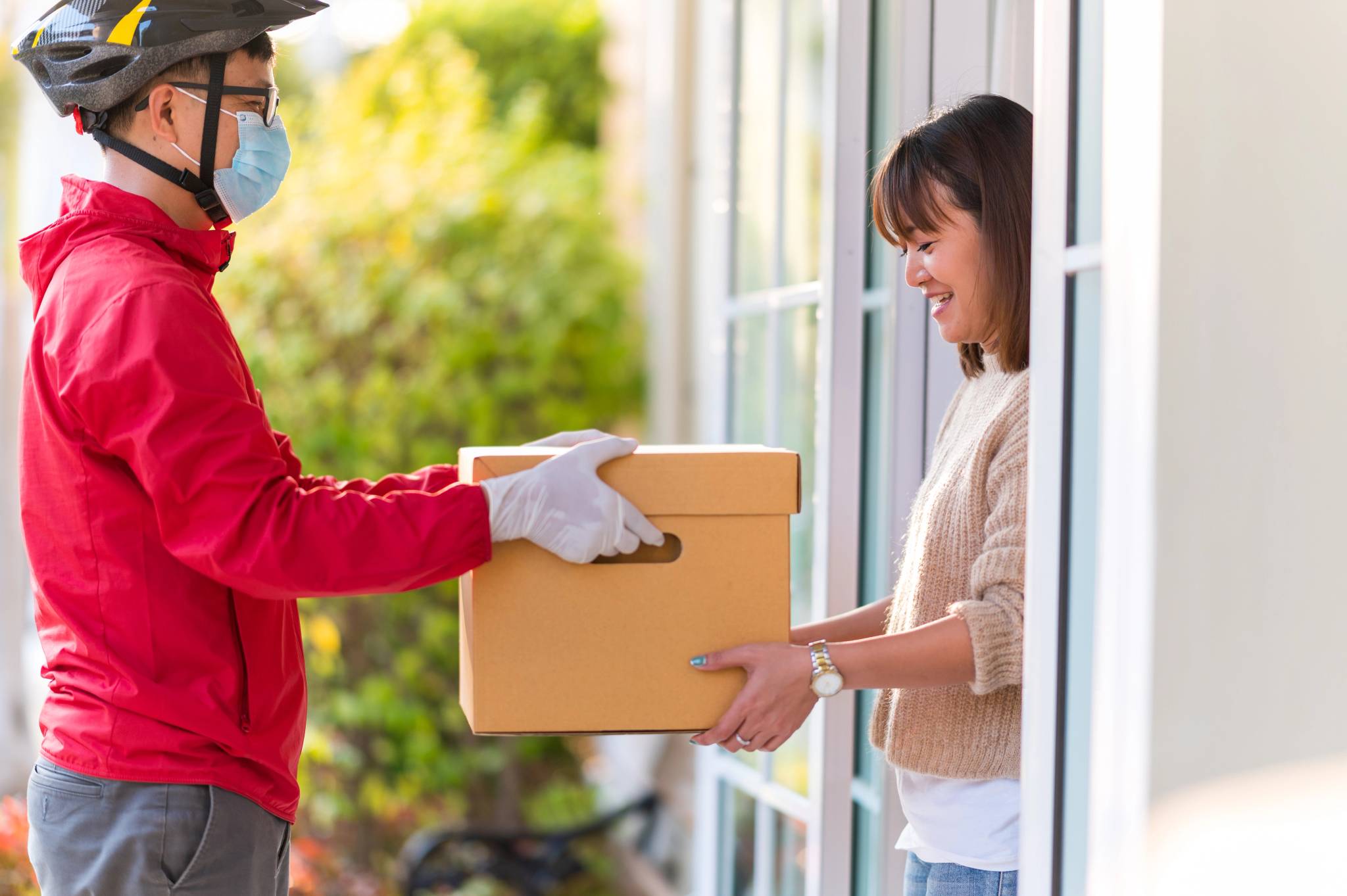 Delivery man giving box to woman by the door.