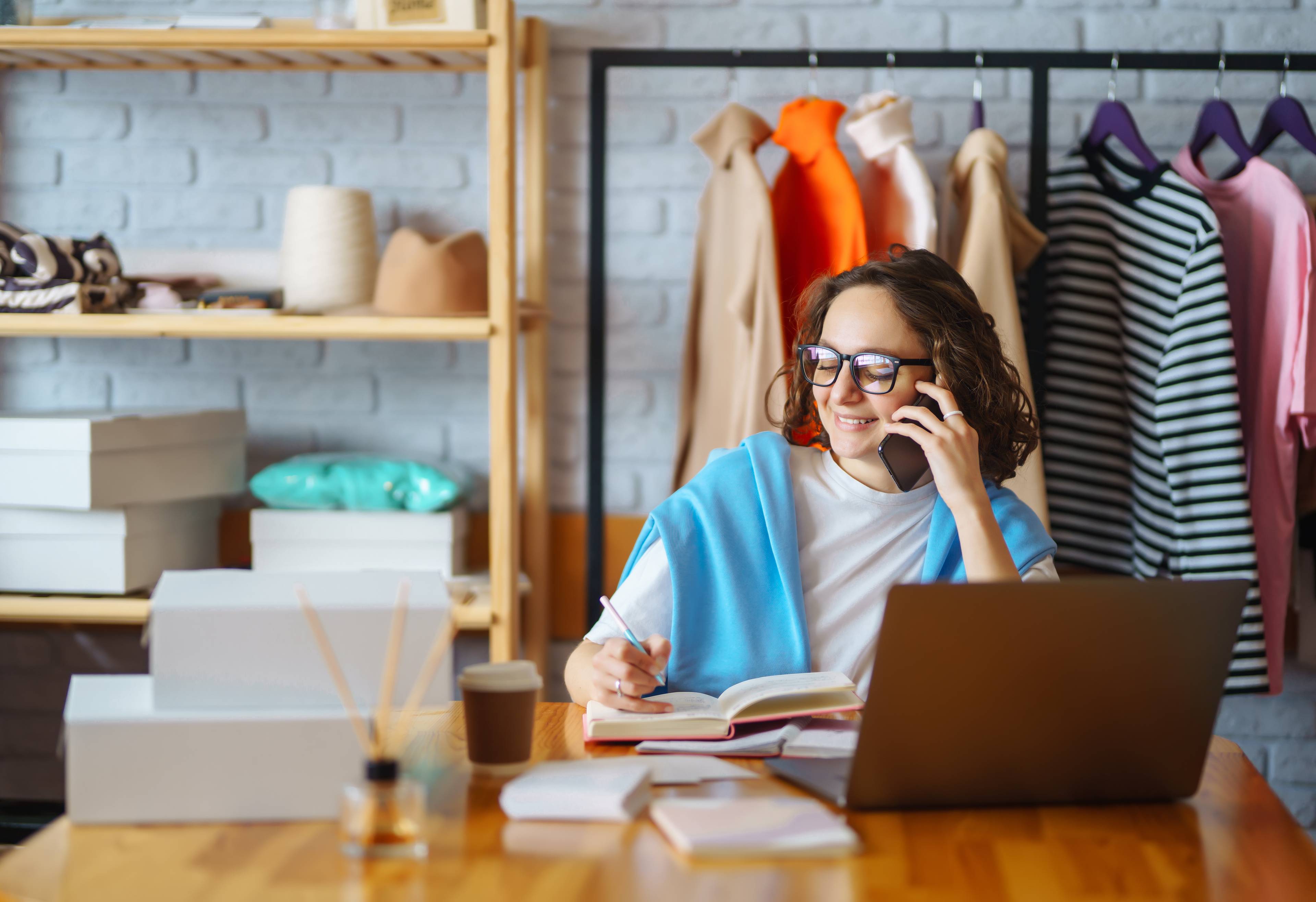Smiling woman takes notes of orders from with laptop
