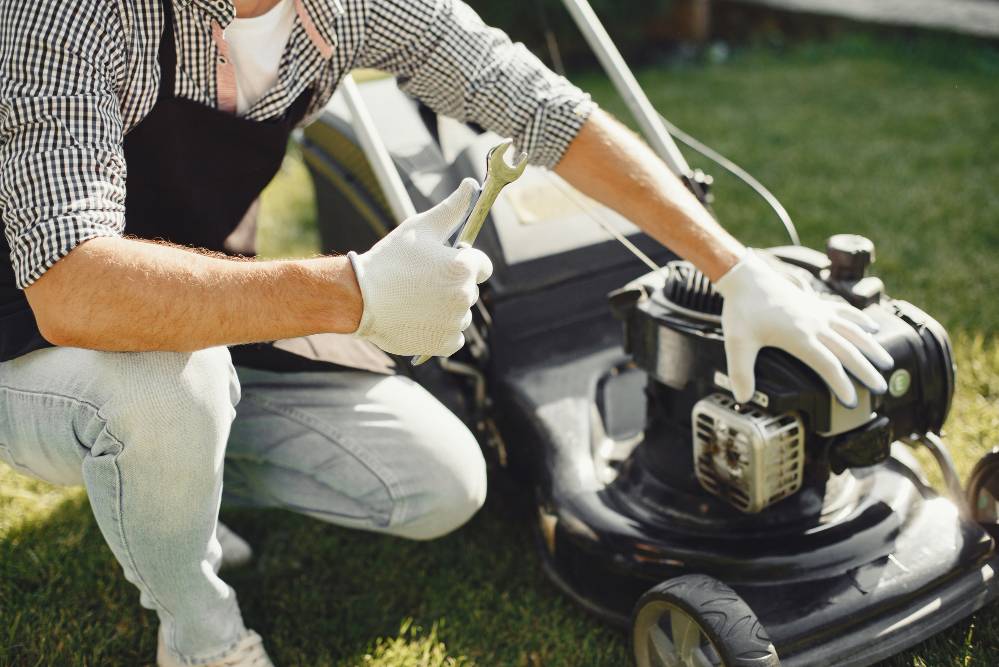 Someone holding a spanner to their mower, ready to fix it.