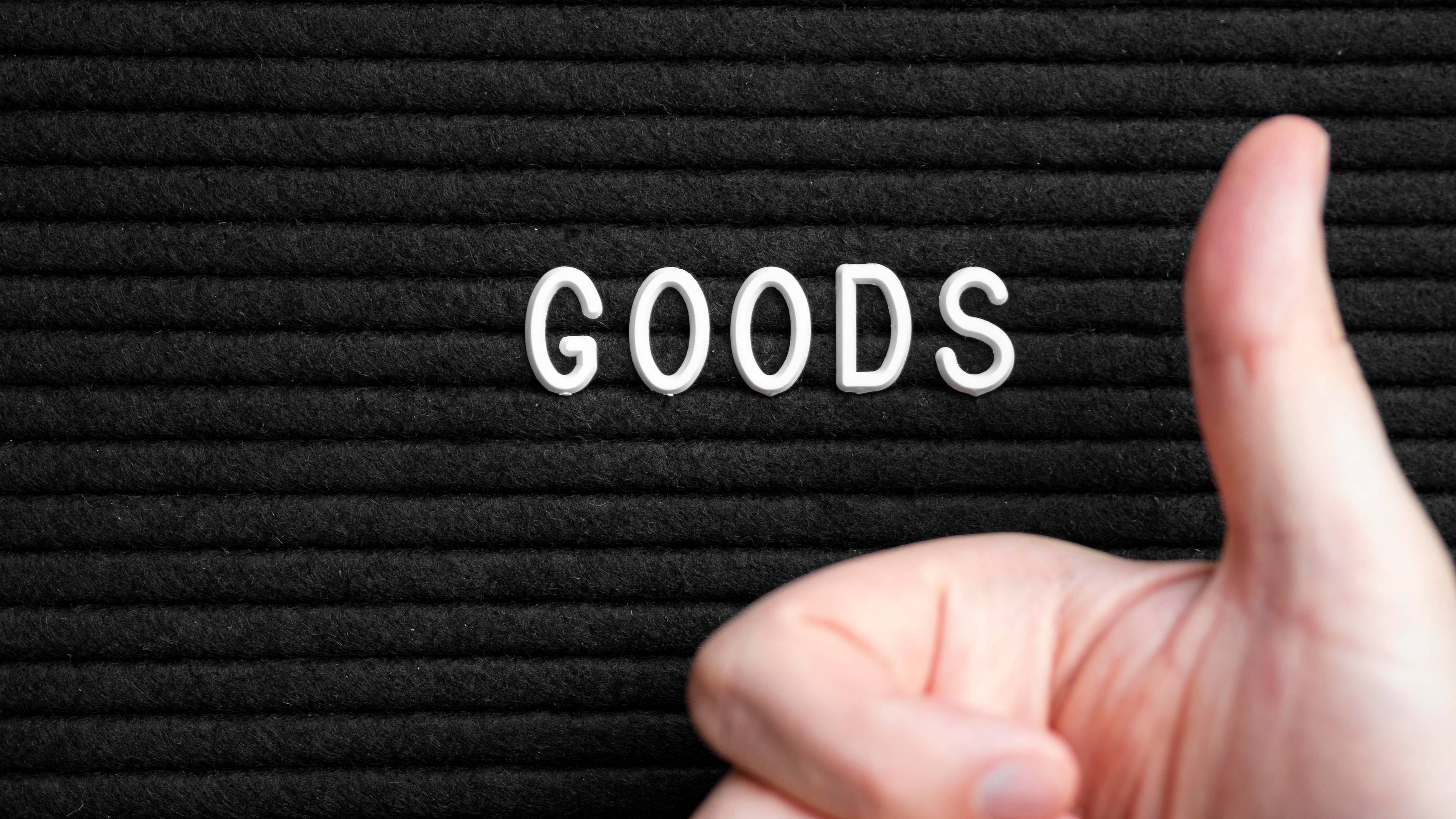 Man holding giving thumbs up and the word GOODS