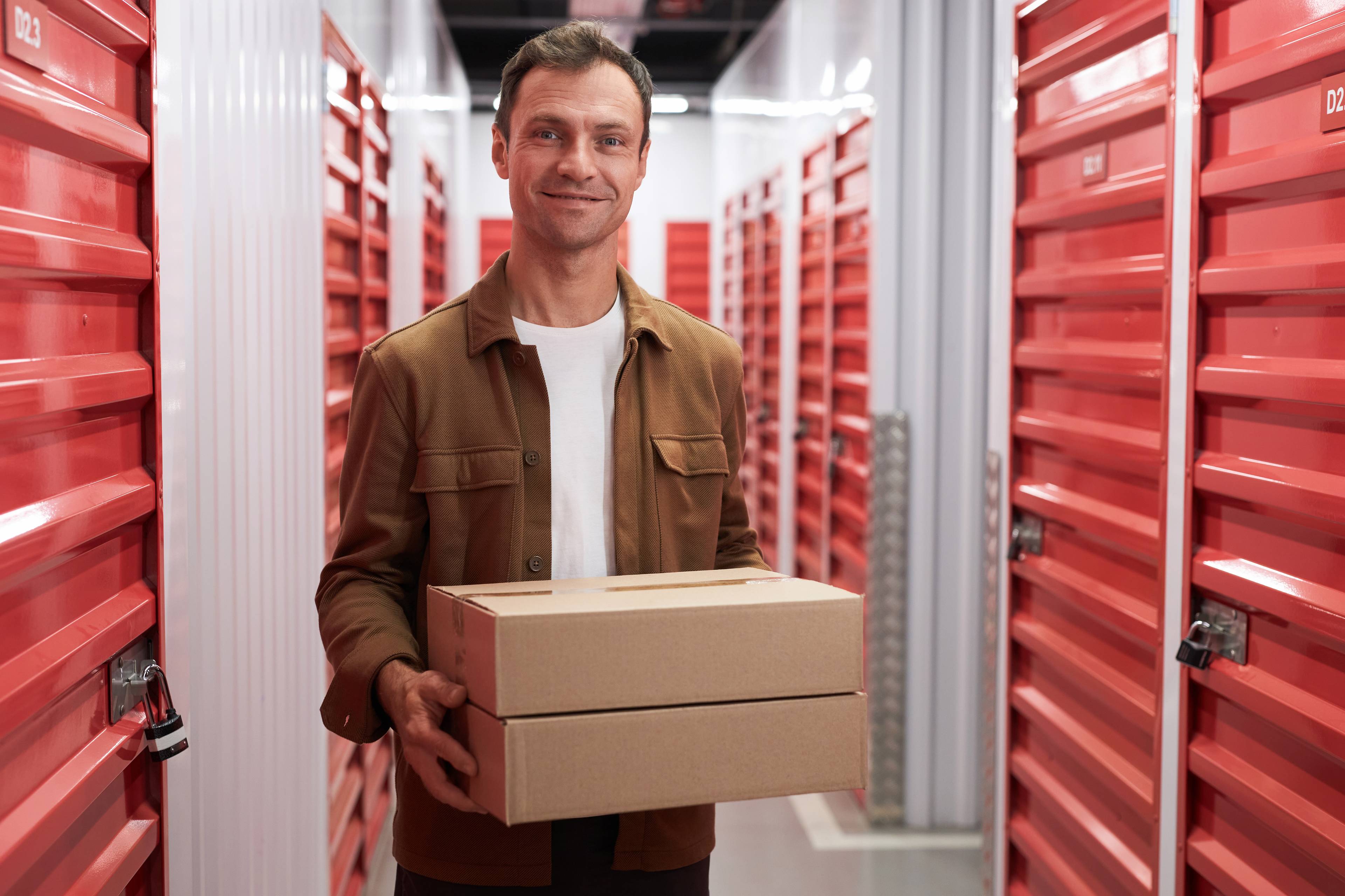 smiling man holding boxes inside storage facility