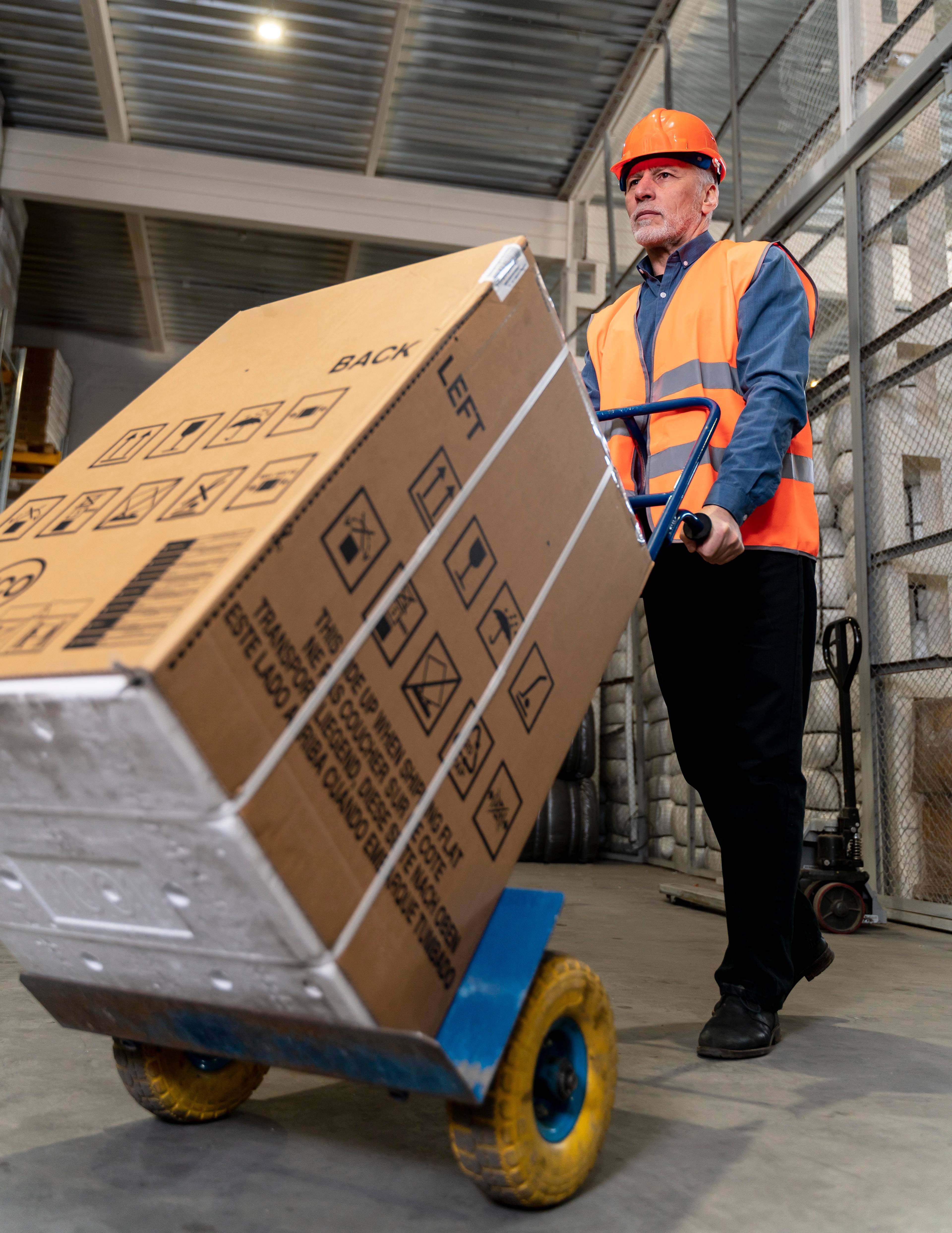 Man with helmet using dollies to move big box