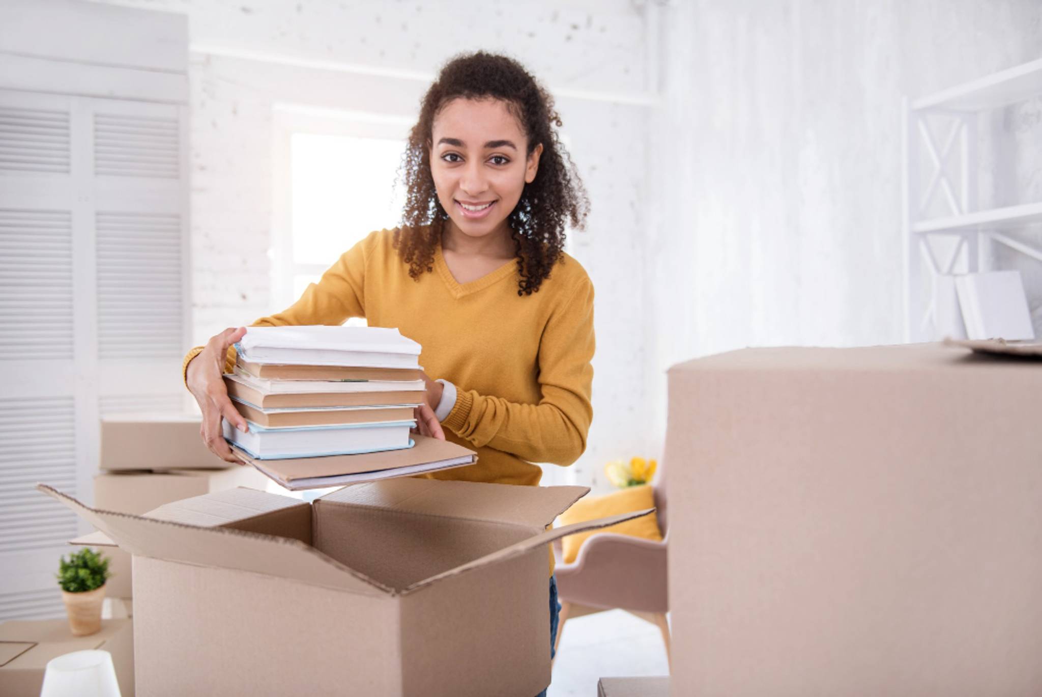 woman packing books in boxes smiling