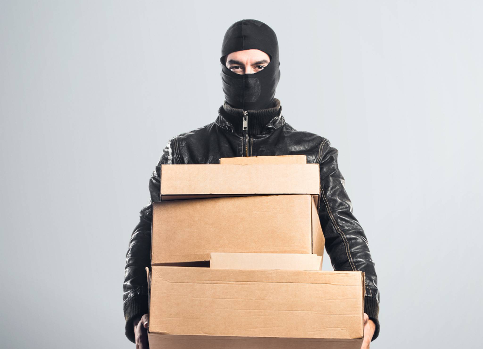Man in balaclava holding boxes