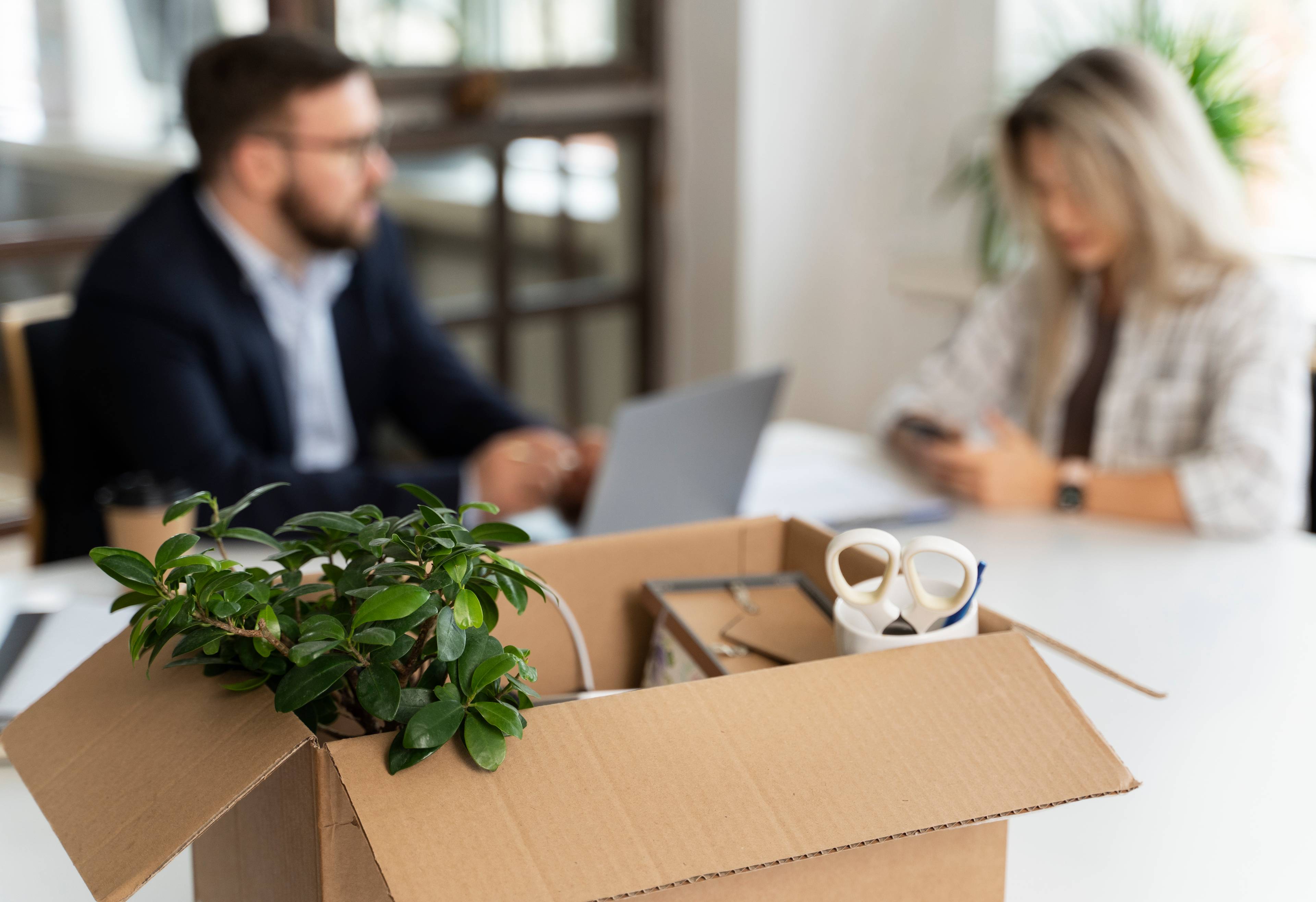 box with in foreground with 2 office workers in background