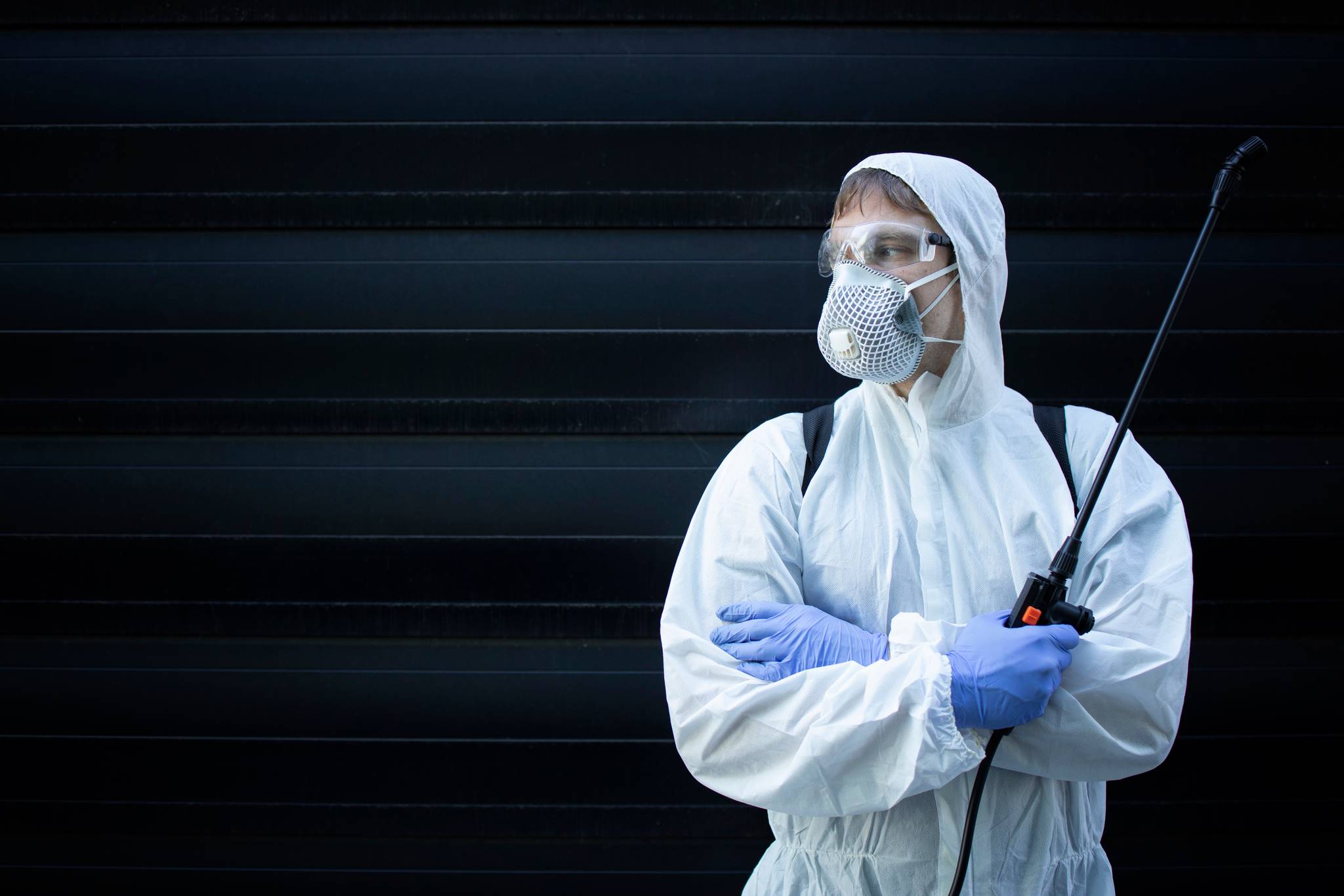 An exterminator standing in front of a wall.