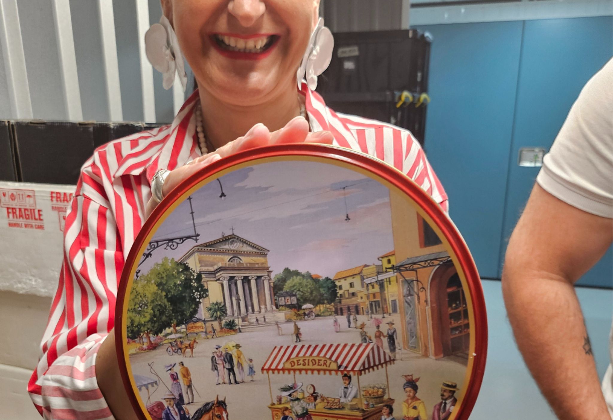 tuscany and taste hold customer holding up china plate smiling in storage facility
