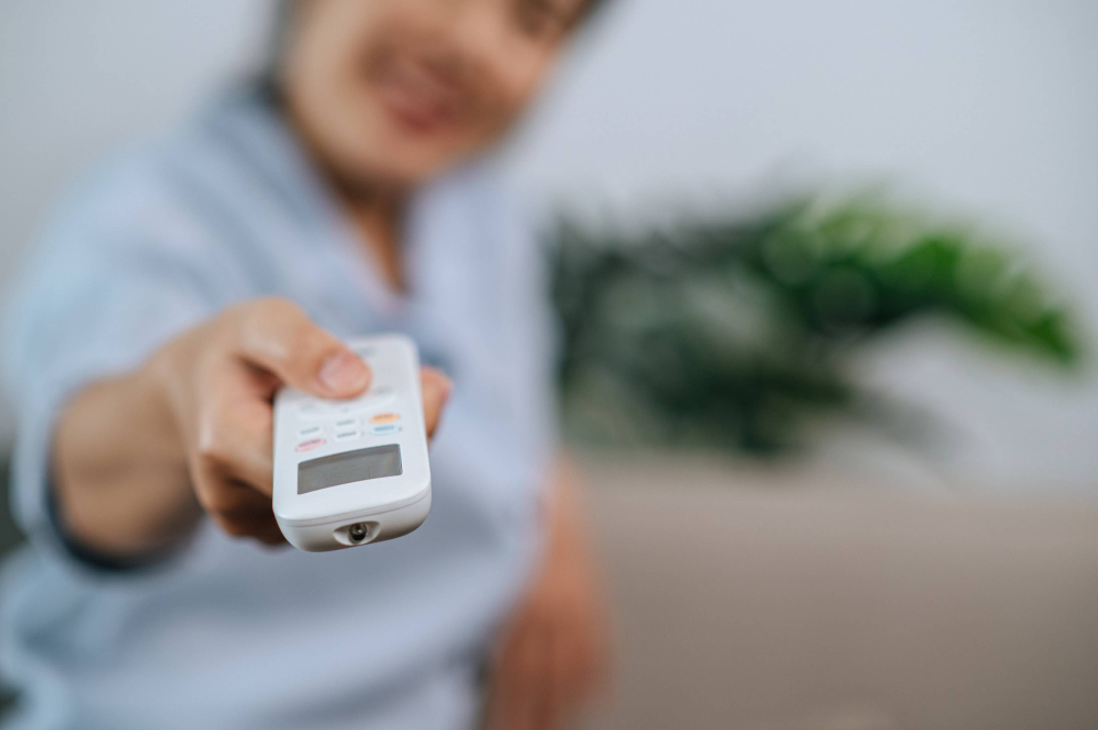Woman holding a climate control remote and pointing it towards the camera