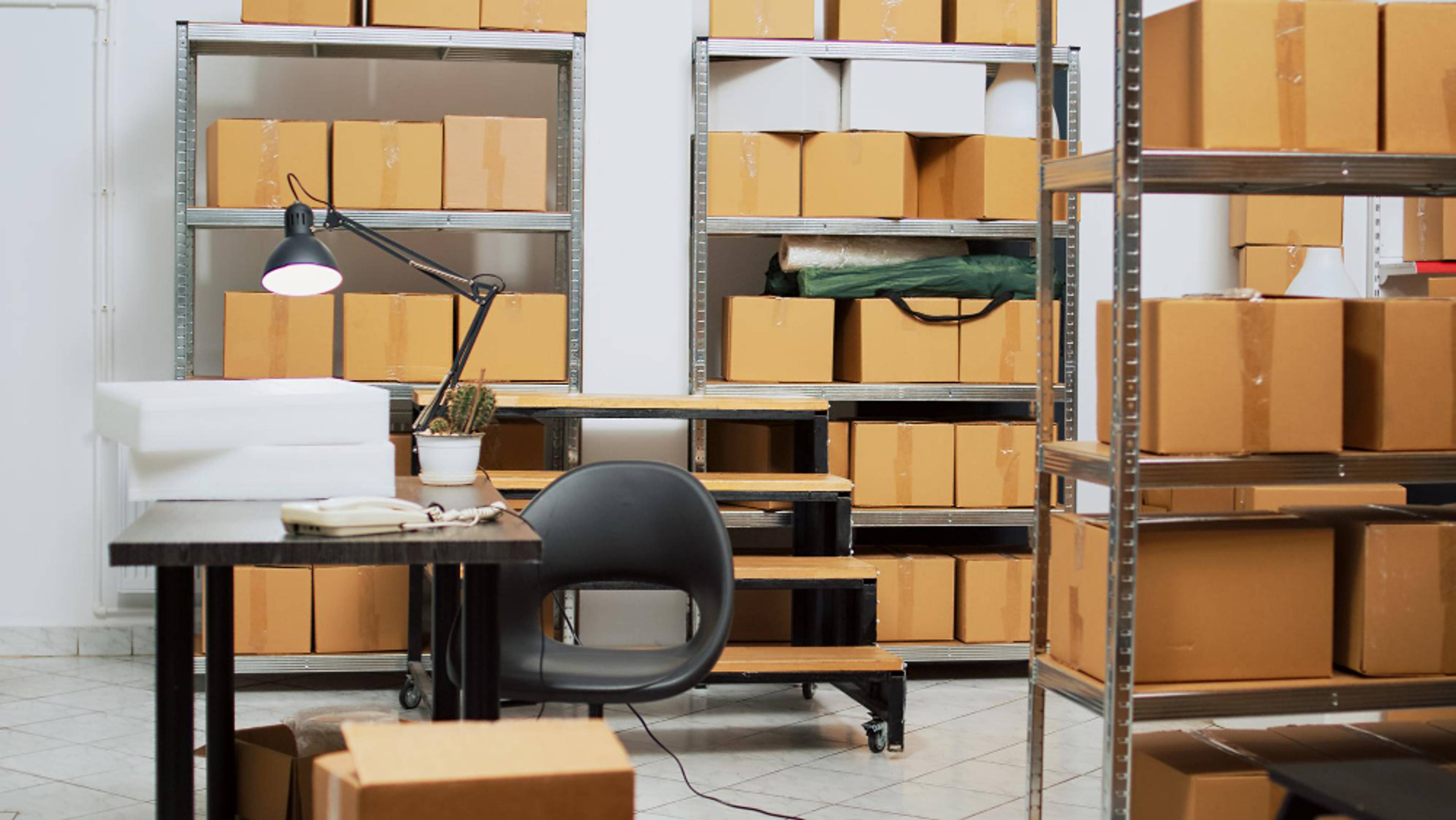 A desk and chair surrounded by shelving units filled with boxes.
