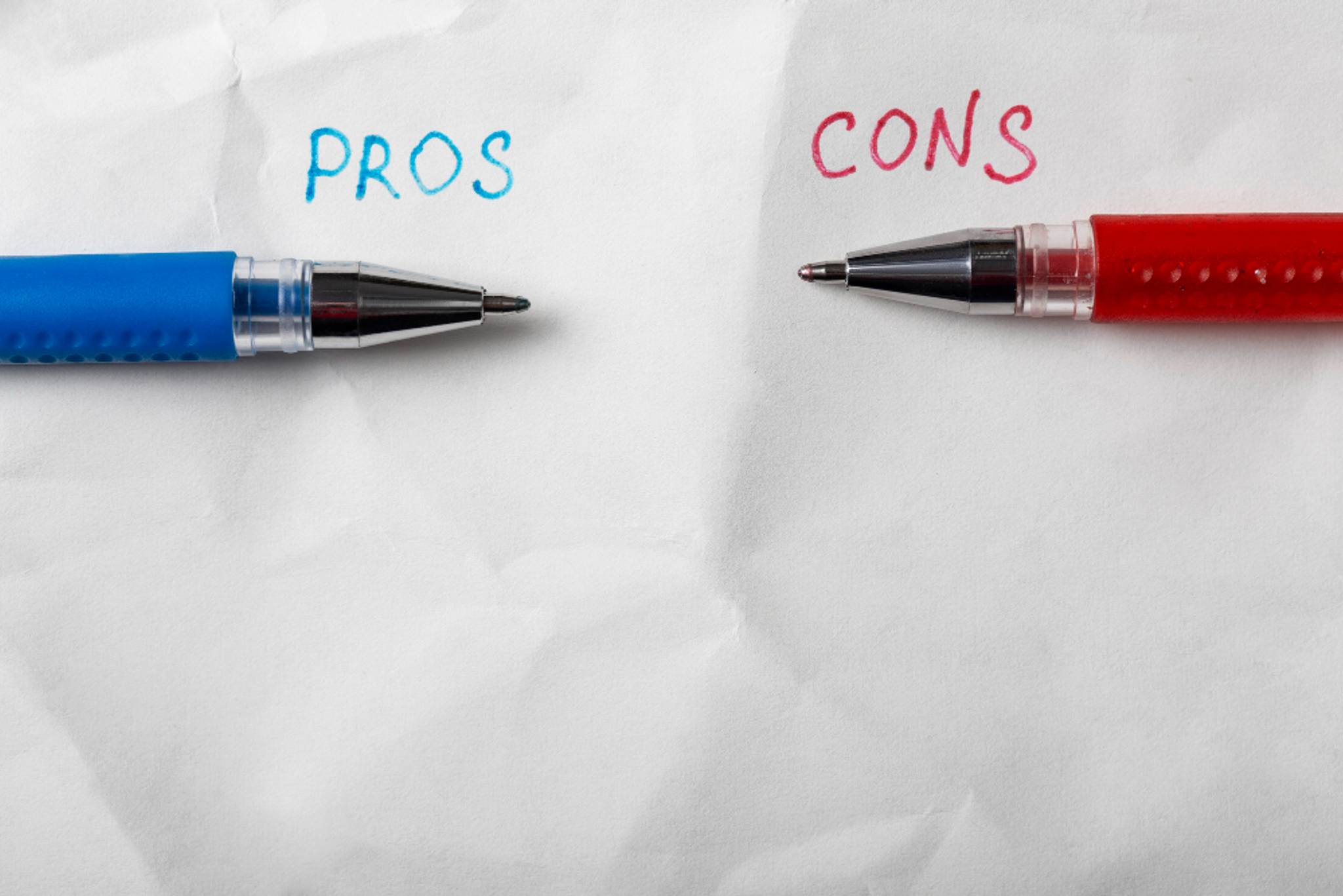 Pros written in blue and cons written on red, on a crumpled piece of paper
