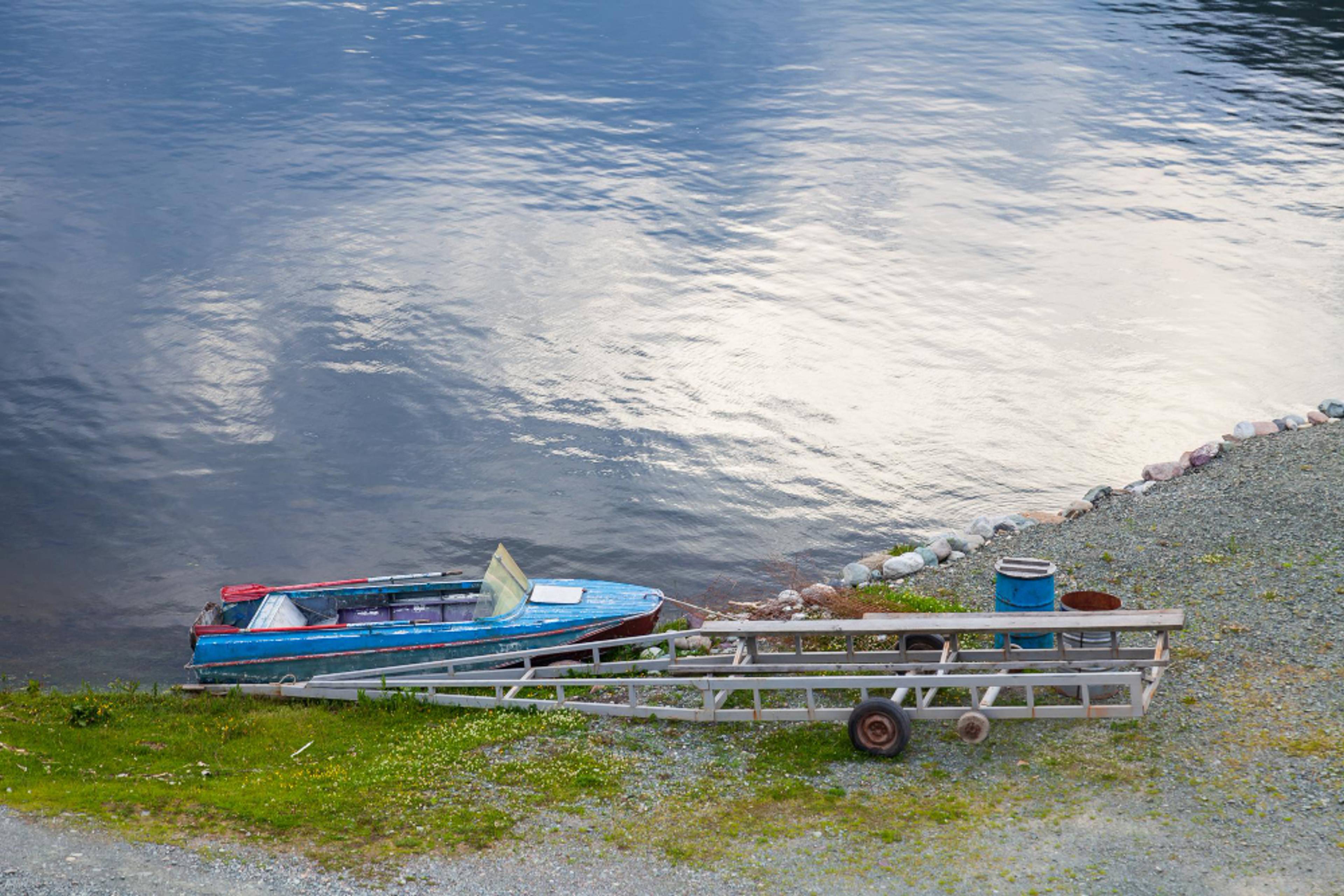 A boat on the side of a lake is connected to a trailer