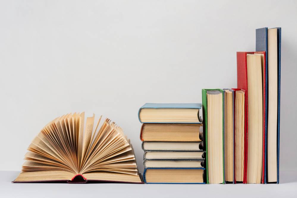 A collection of books, some upright and some stacked