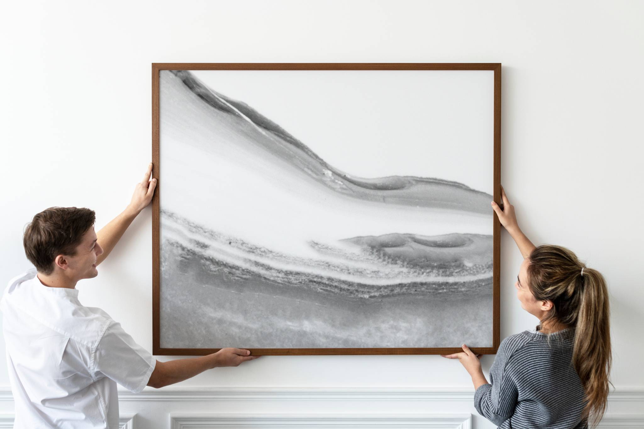 Woman and man arranging framed picture
