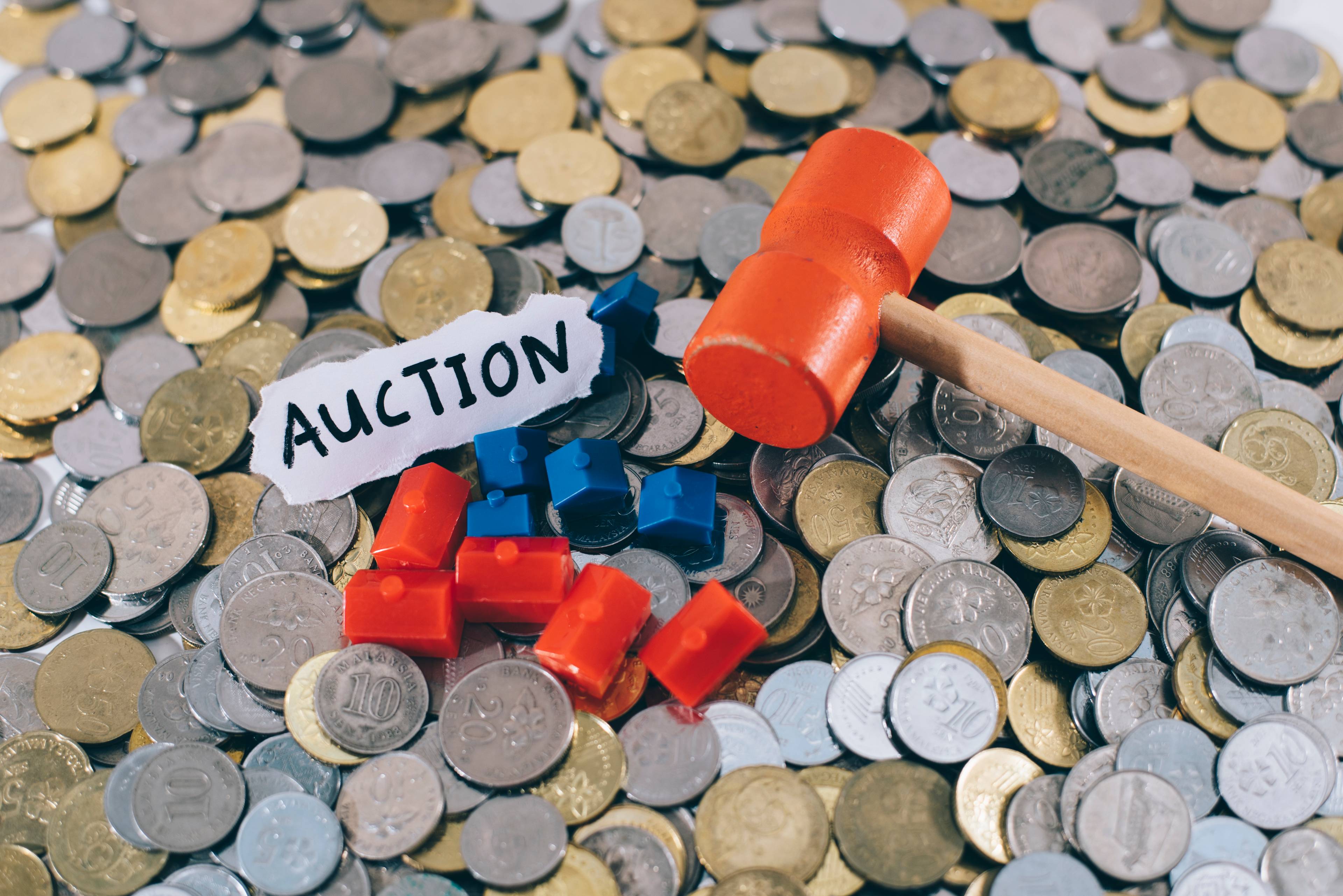 Coins laid out, with the word "auction" in a piece of paper and an orange gavel.