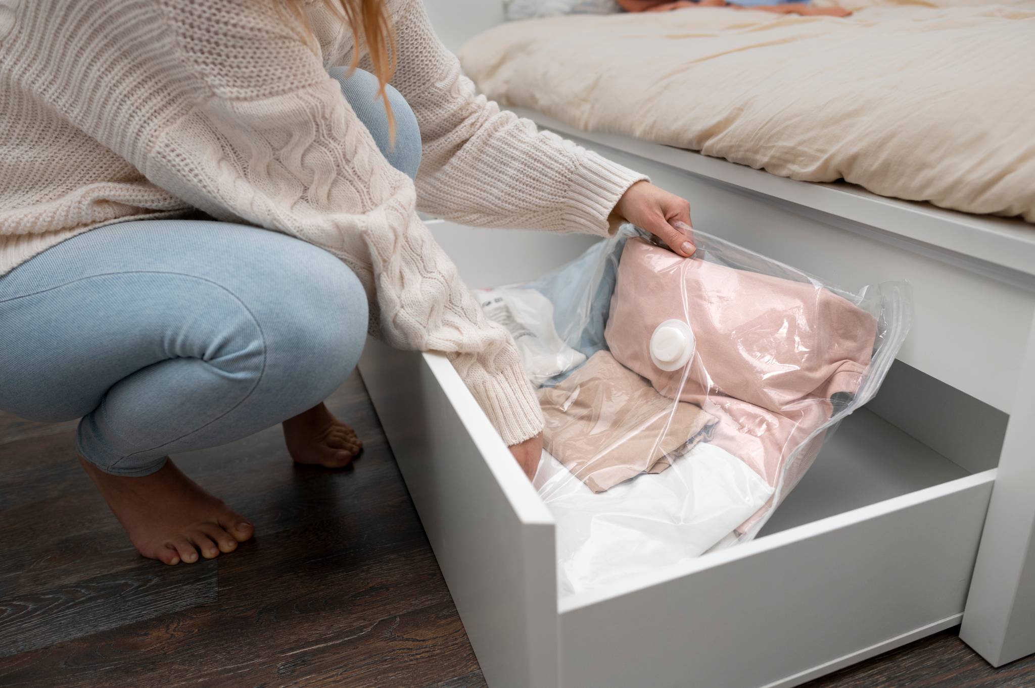 woman packing clothing in protective materials in bed wardrobe