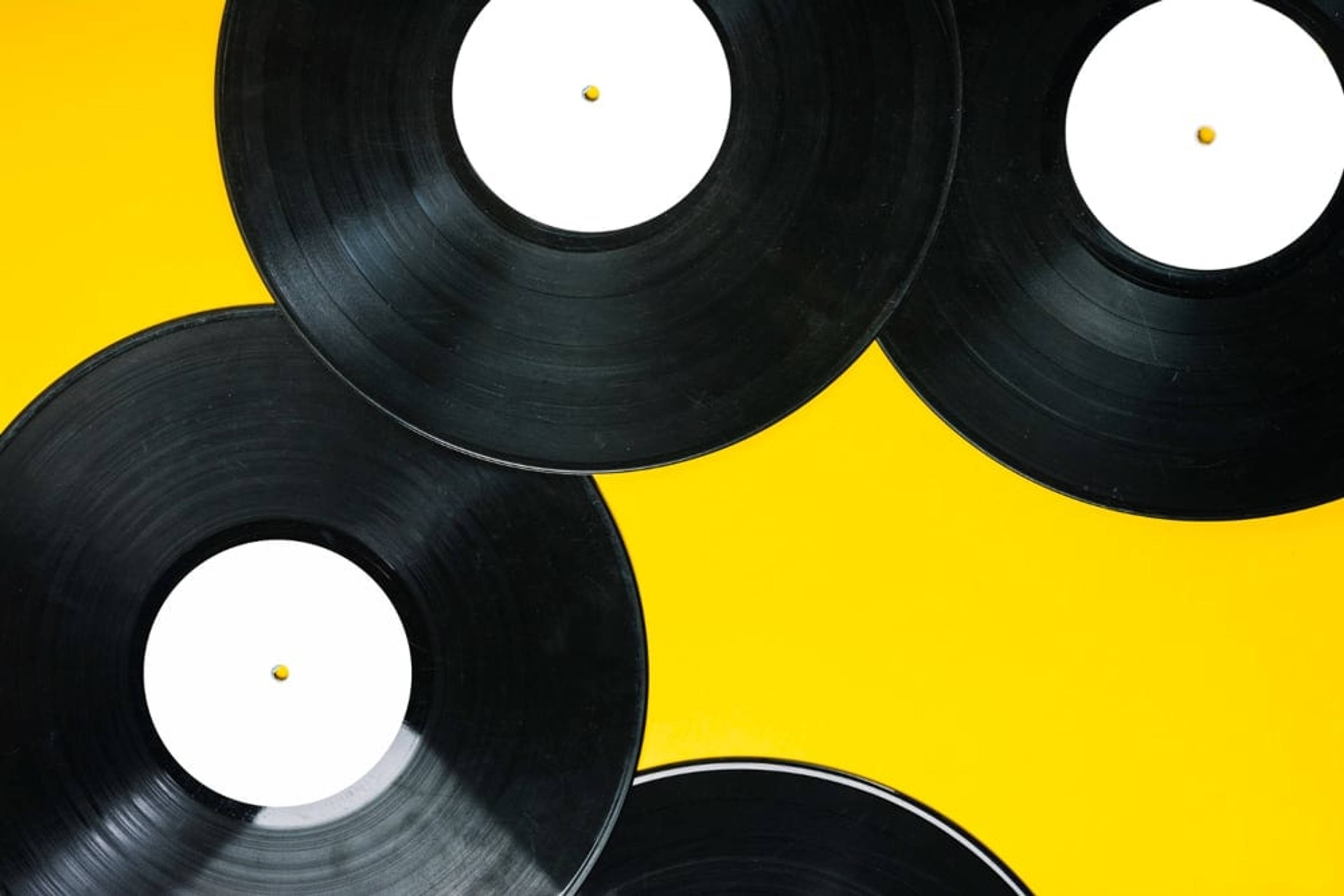 Vinyl records laying on a yellow background