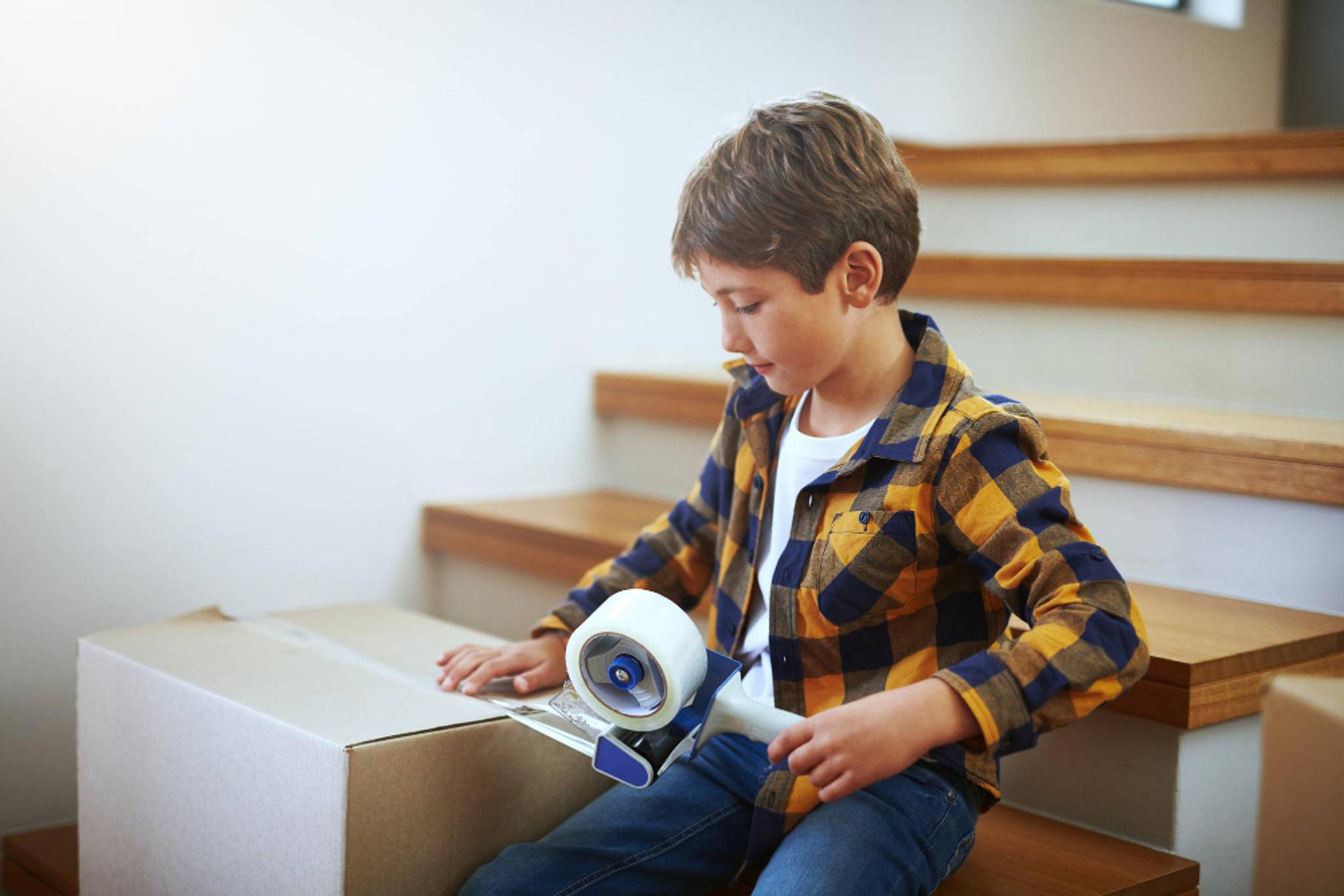 boy applying sellotape to box for house move