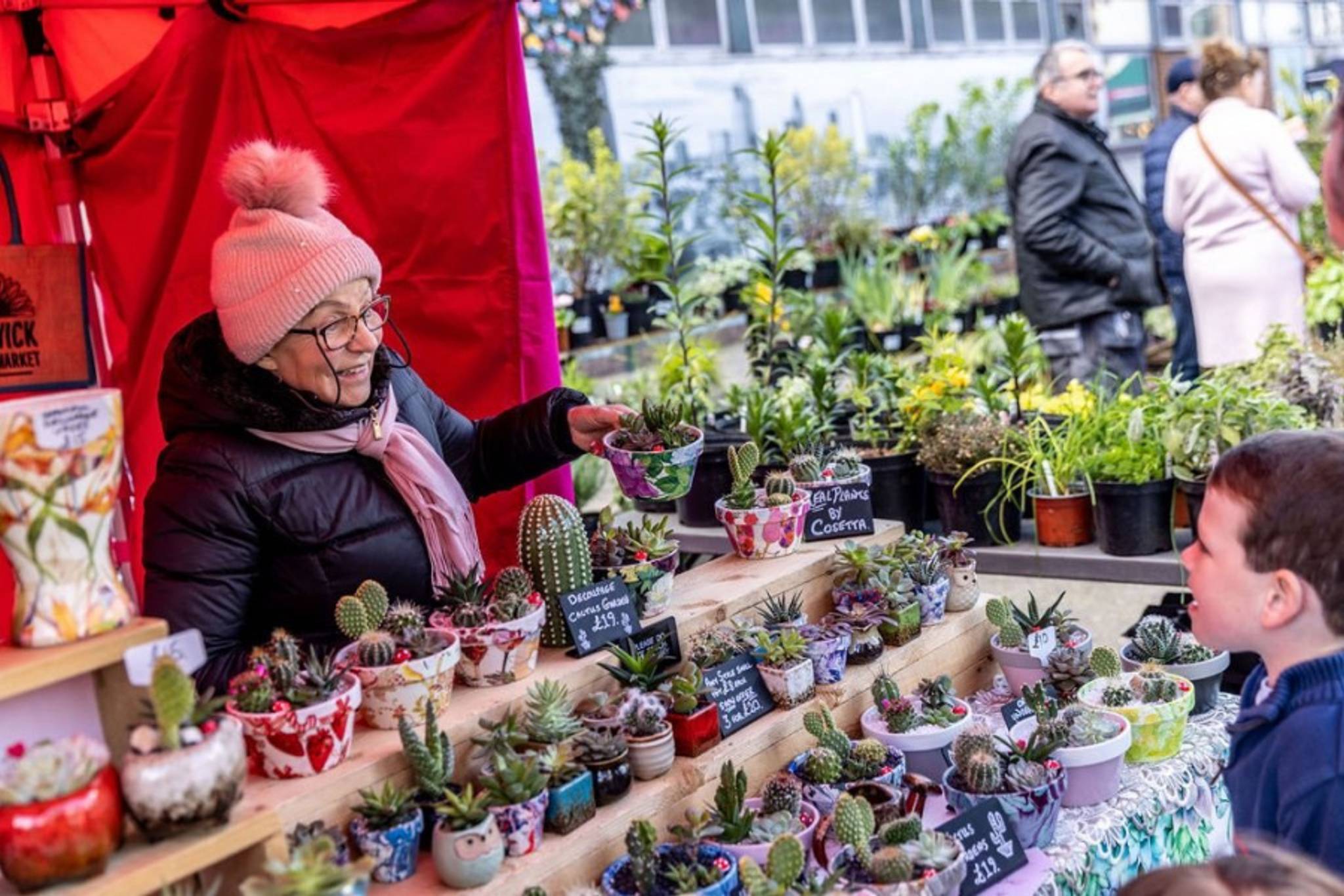 lady at flower stall smiling with young boy customer