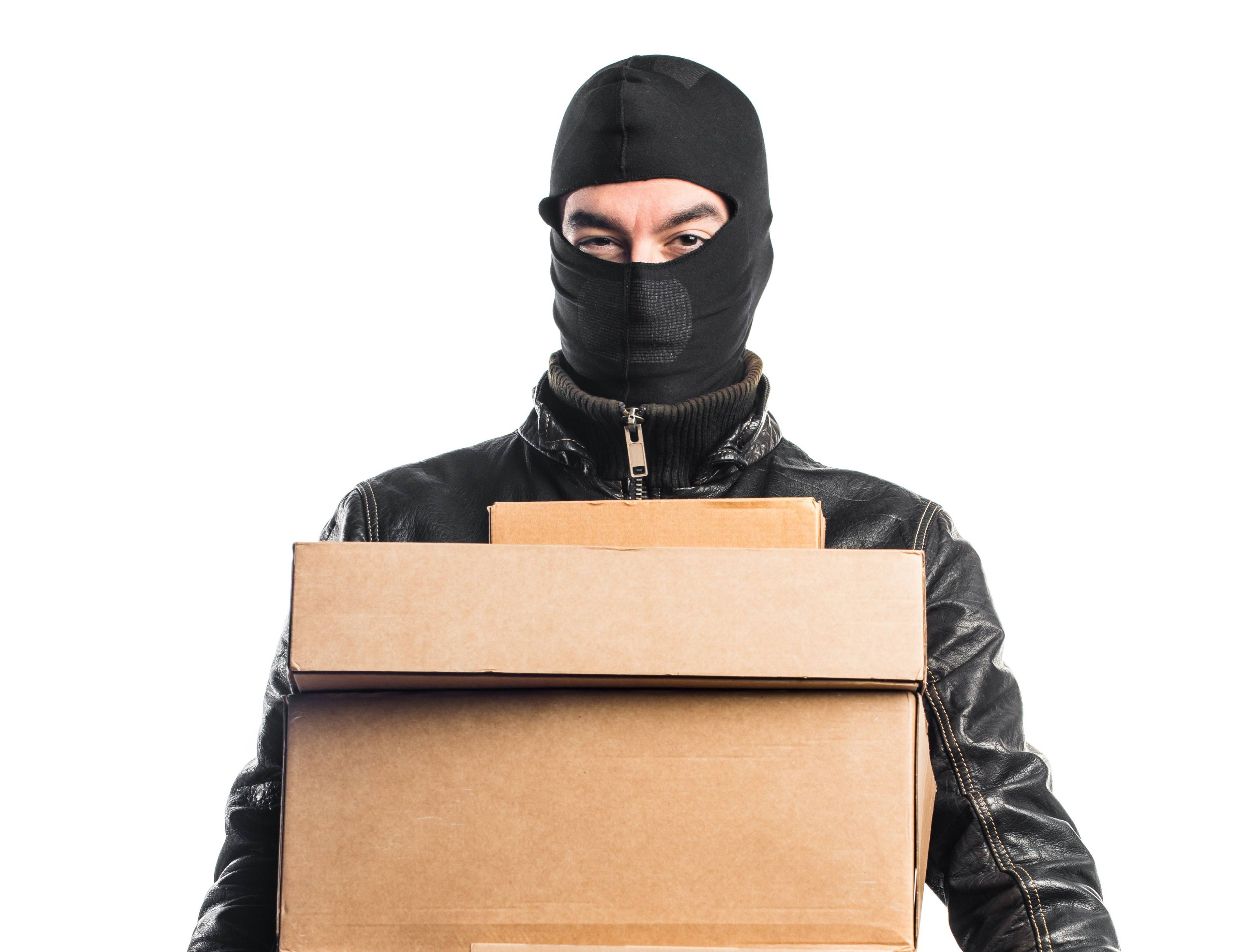 Man in balaclava holding boxes