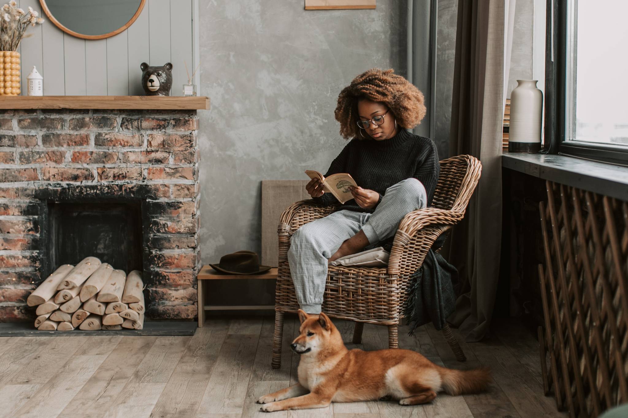 woman sitting down and reading with dog in quaint living room