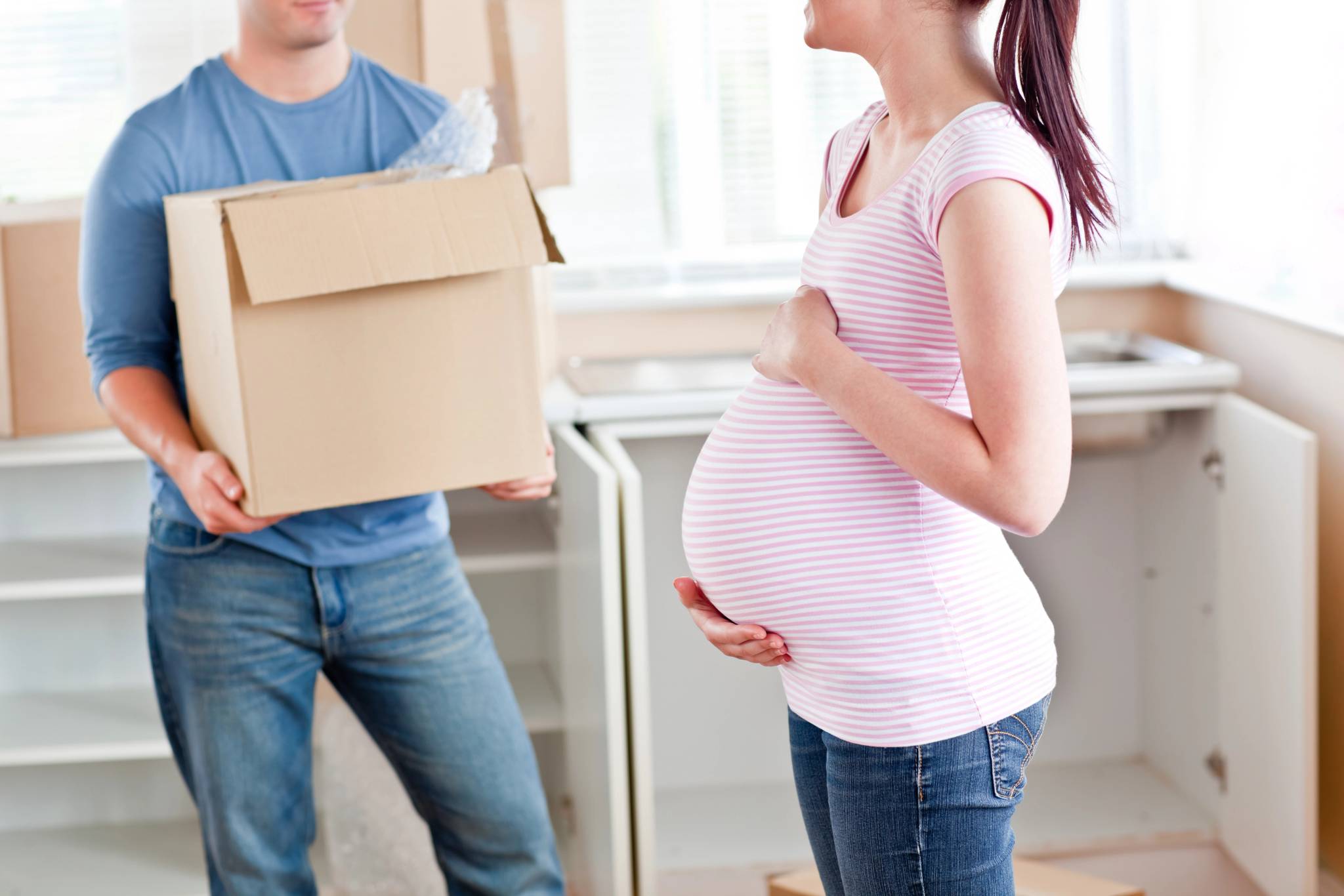 Close-up of a pregnant woman talking to her husband who is holding a cardboard