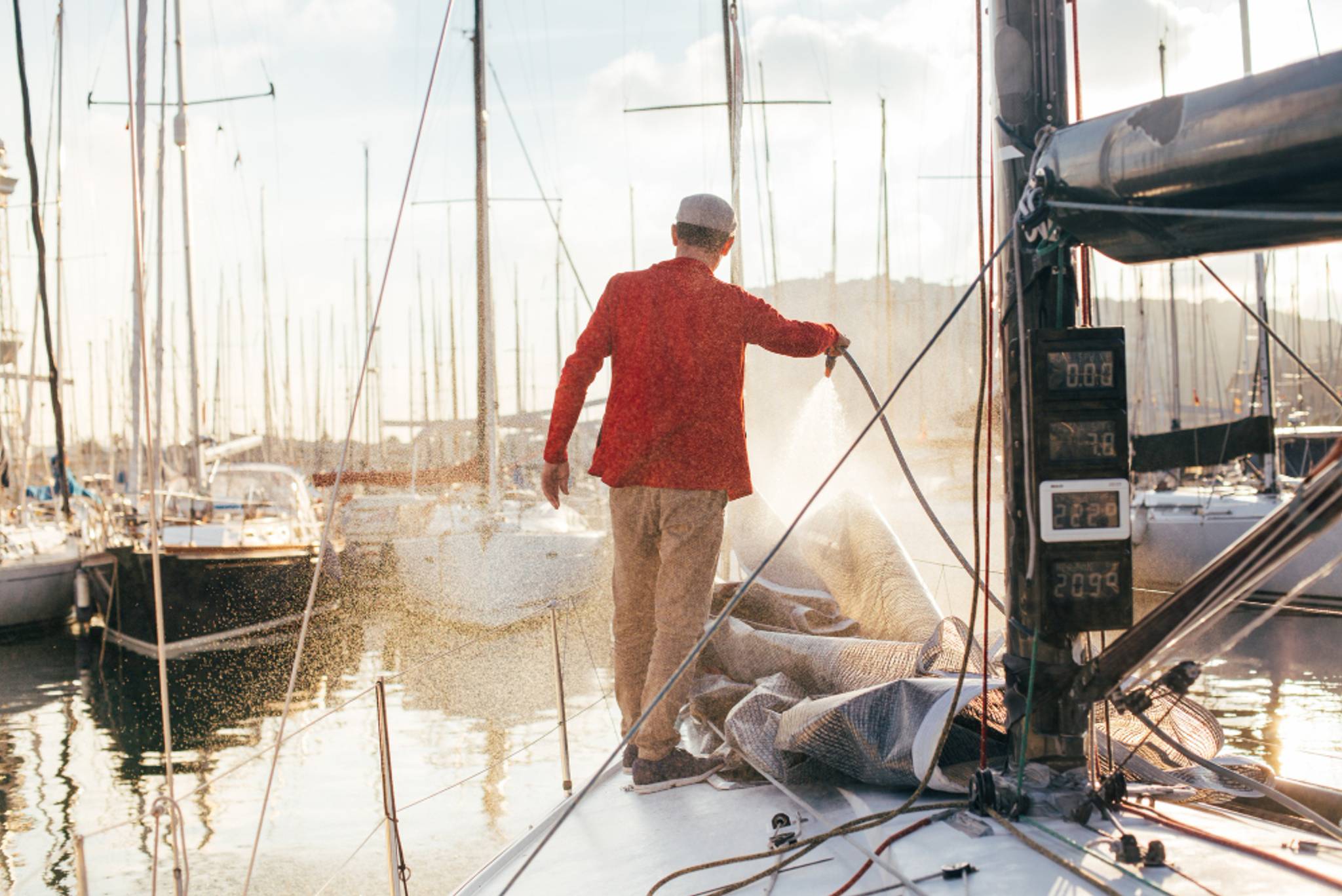 Man cleaning a boat in a marina during a sunset
