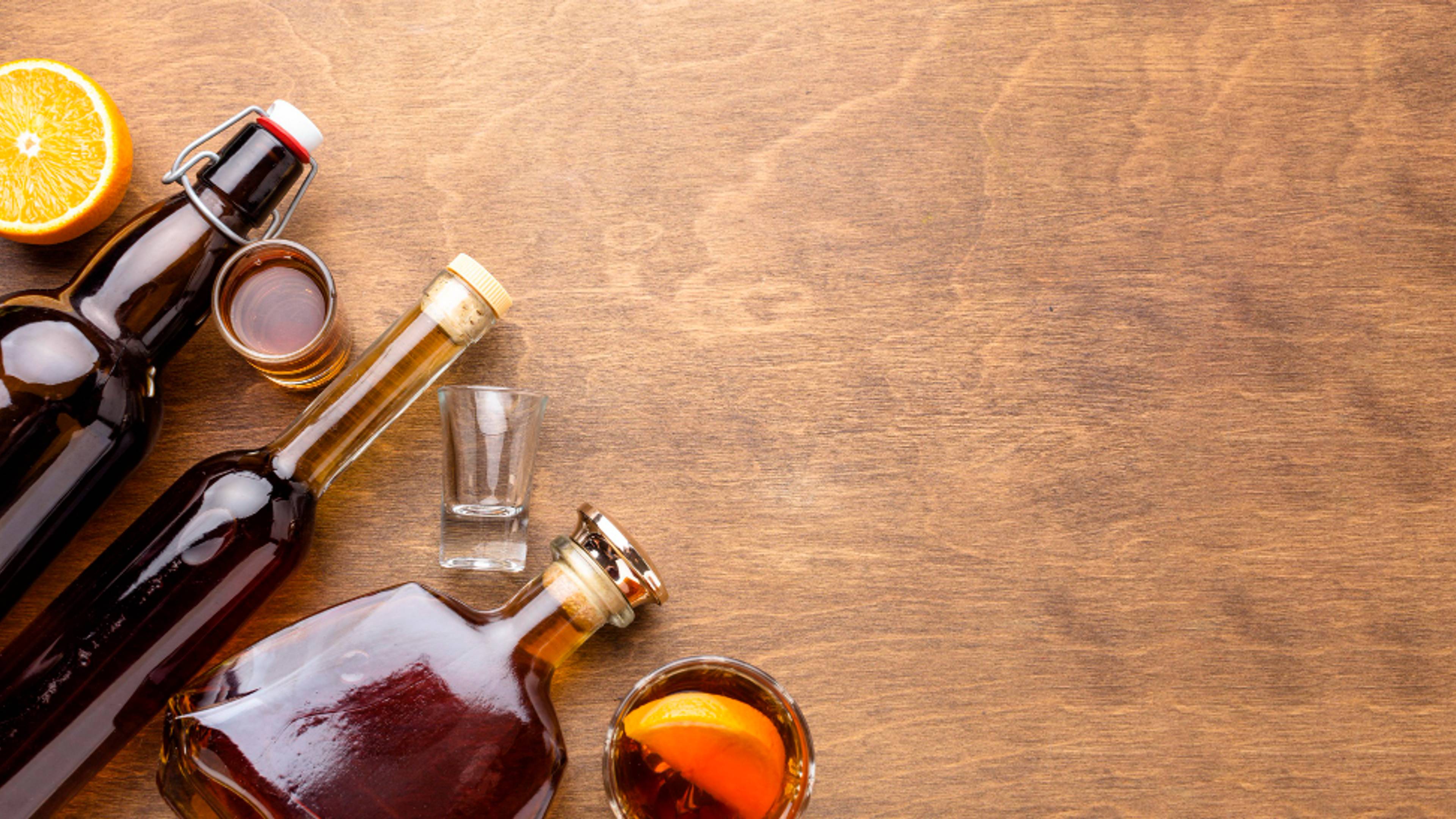 Line of alcohol bottles coming from the corner of the image, along with glasses and accompaniments