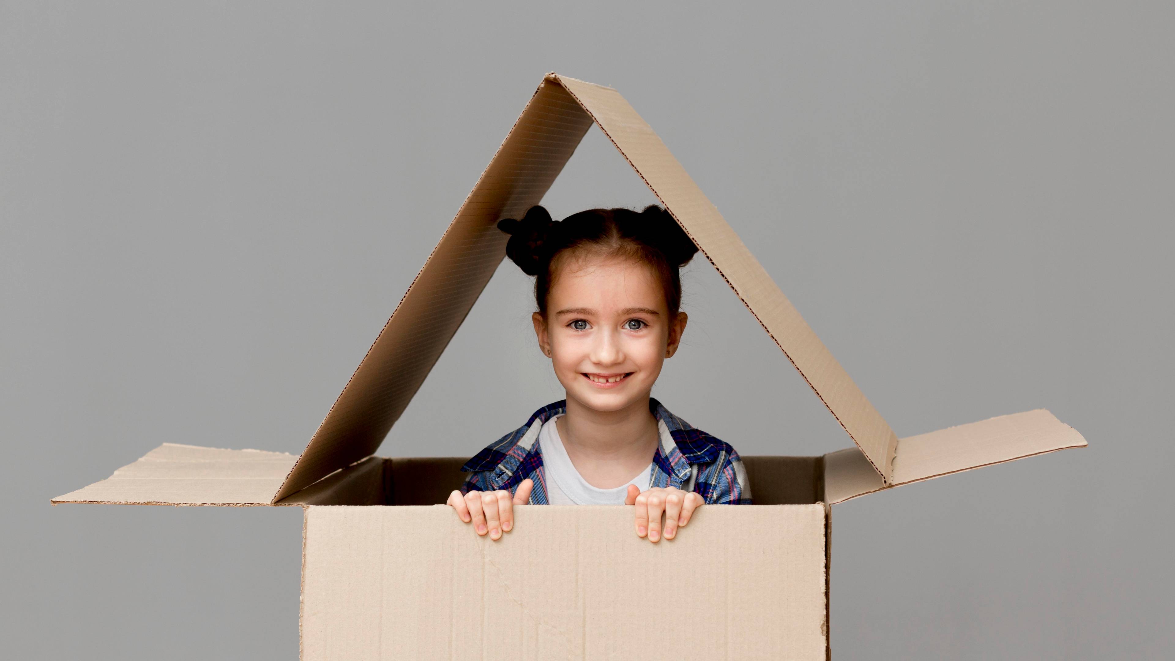 Girl playing in a makeshift cardboard house