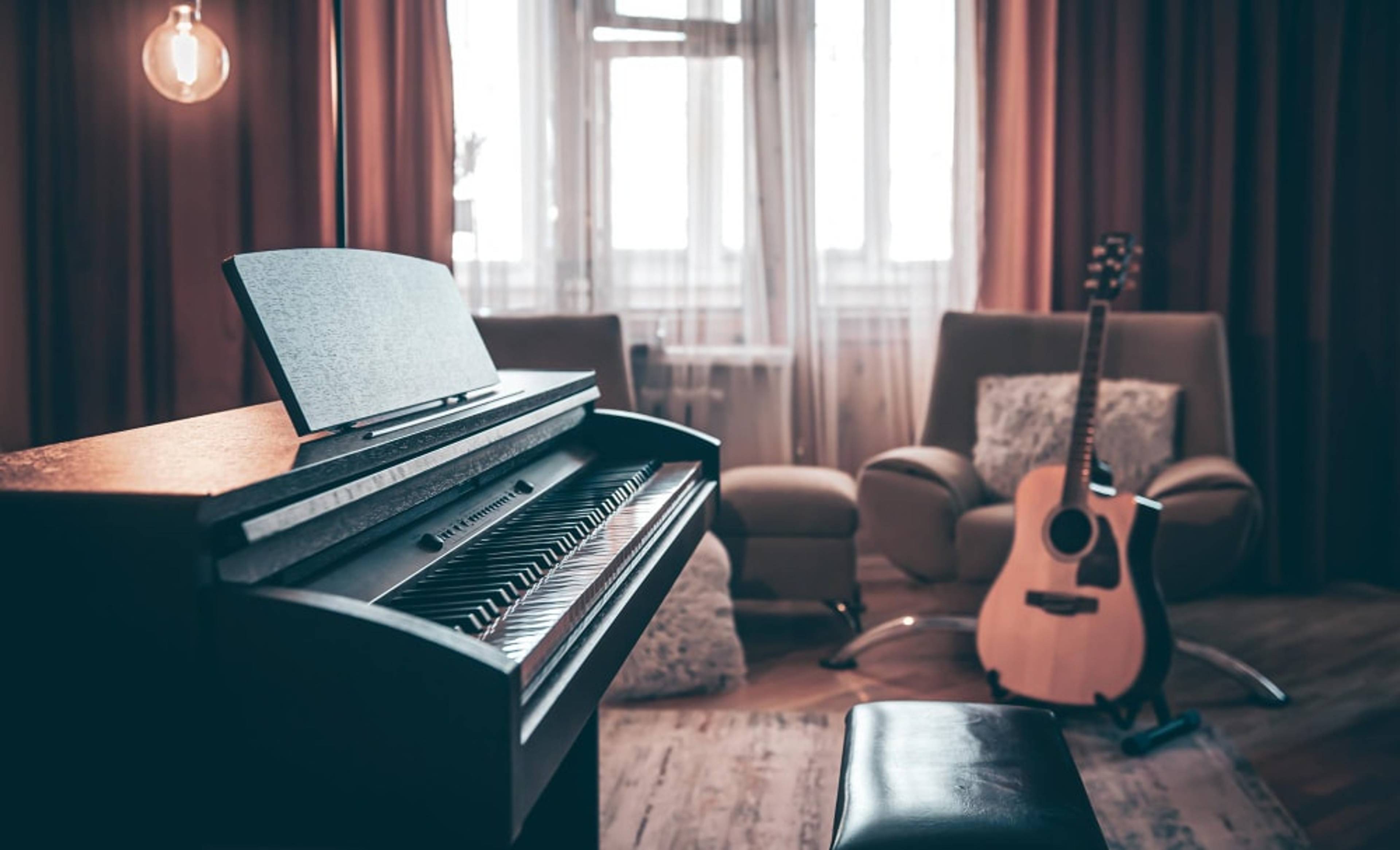 A piano with a guitar in a cosy room