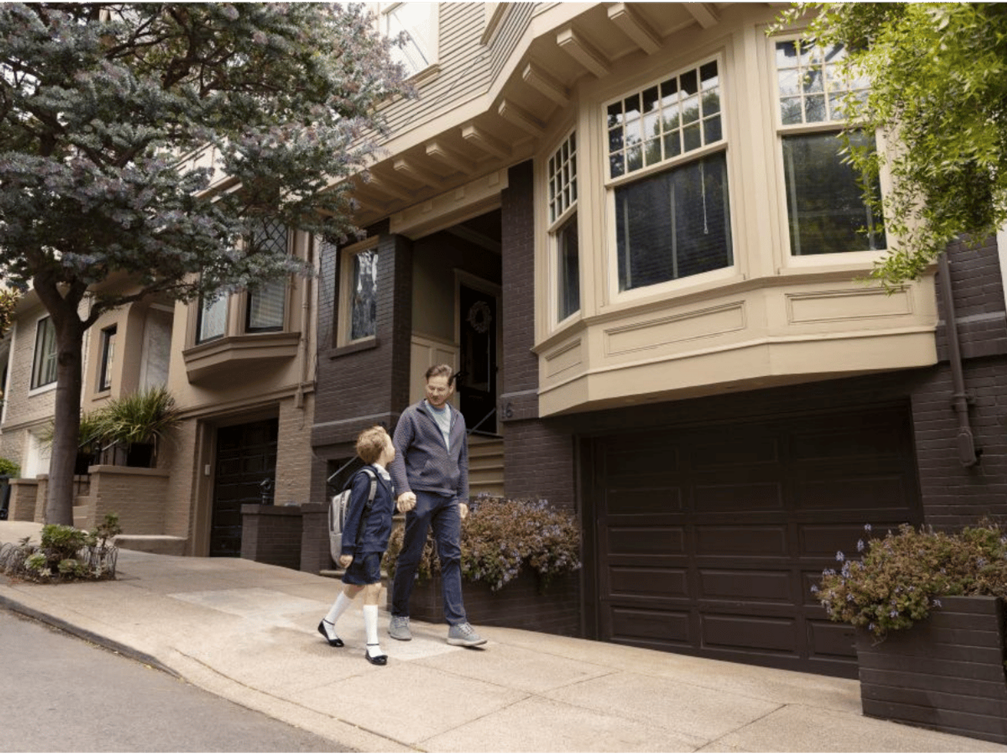 father walking son to school past large uk homes