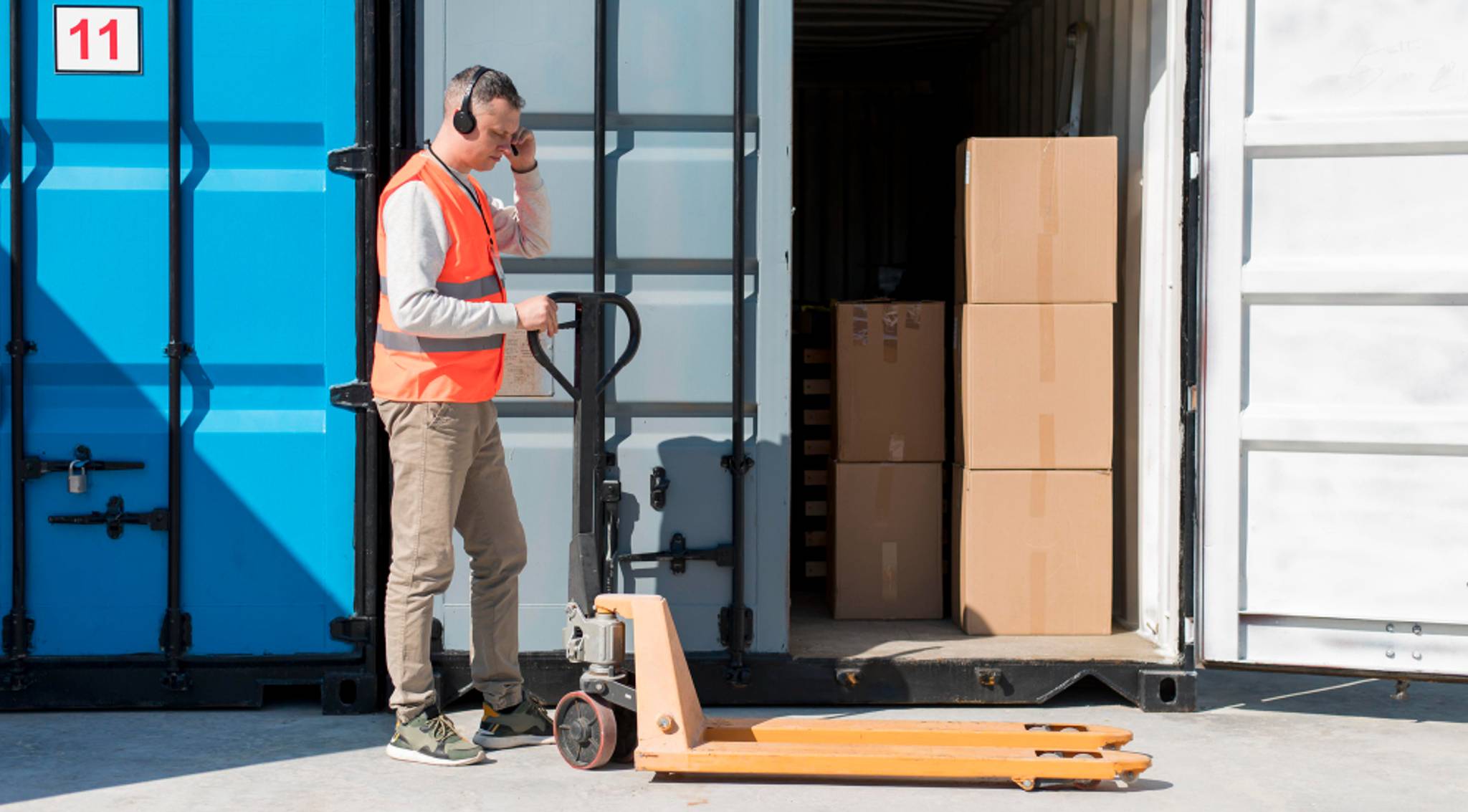 man with pallet trolley outside container storage units