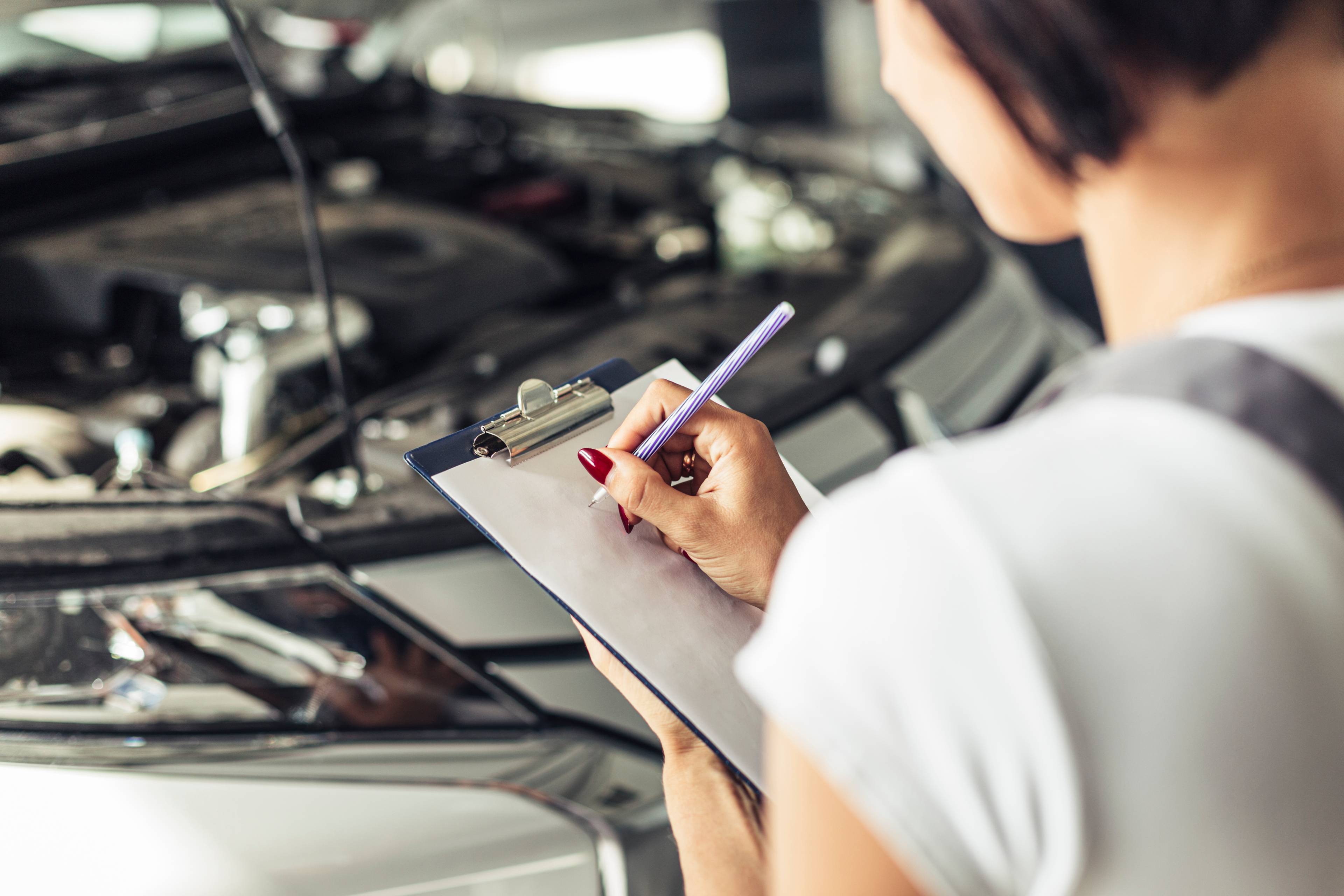 High angle shot of a woman filling out a form on a clipboard.