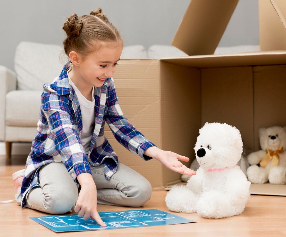 girl with teddy and box in new house