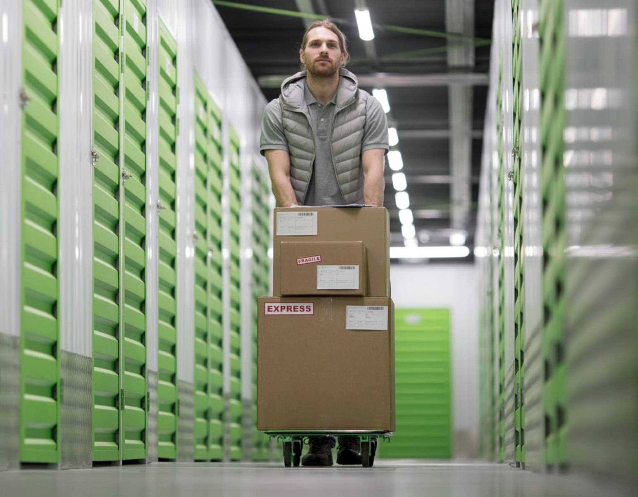 man wheeling boxes past storage units