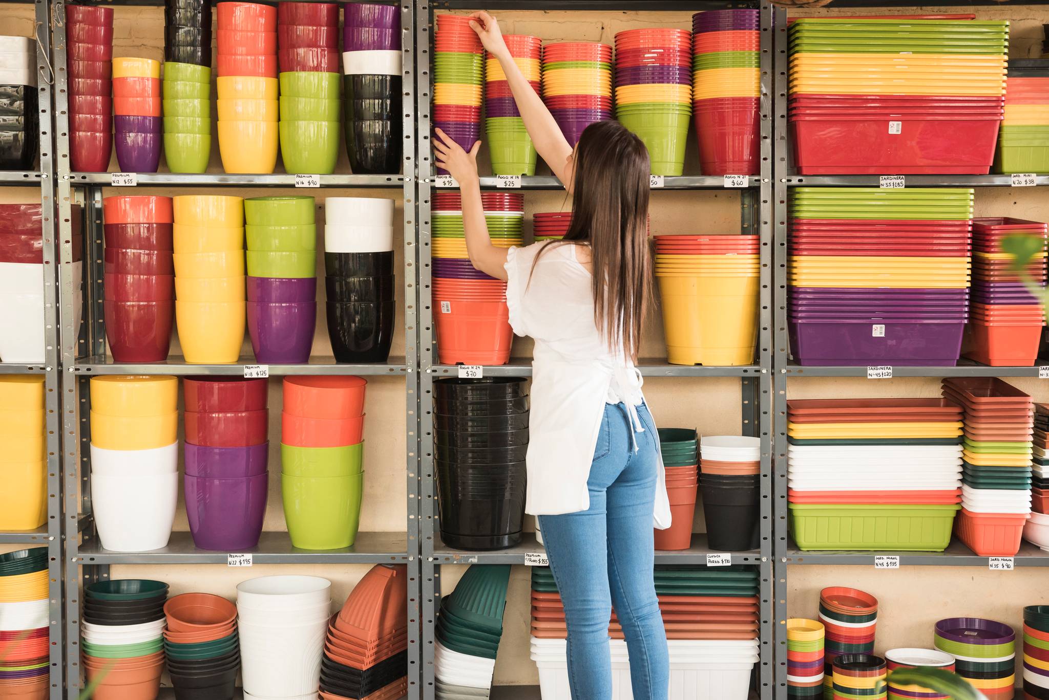 Woman placing stack of pots in shelves