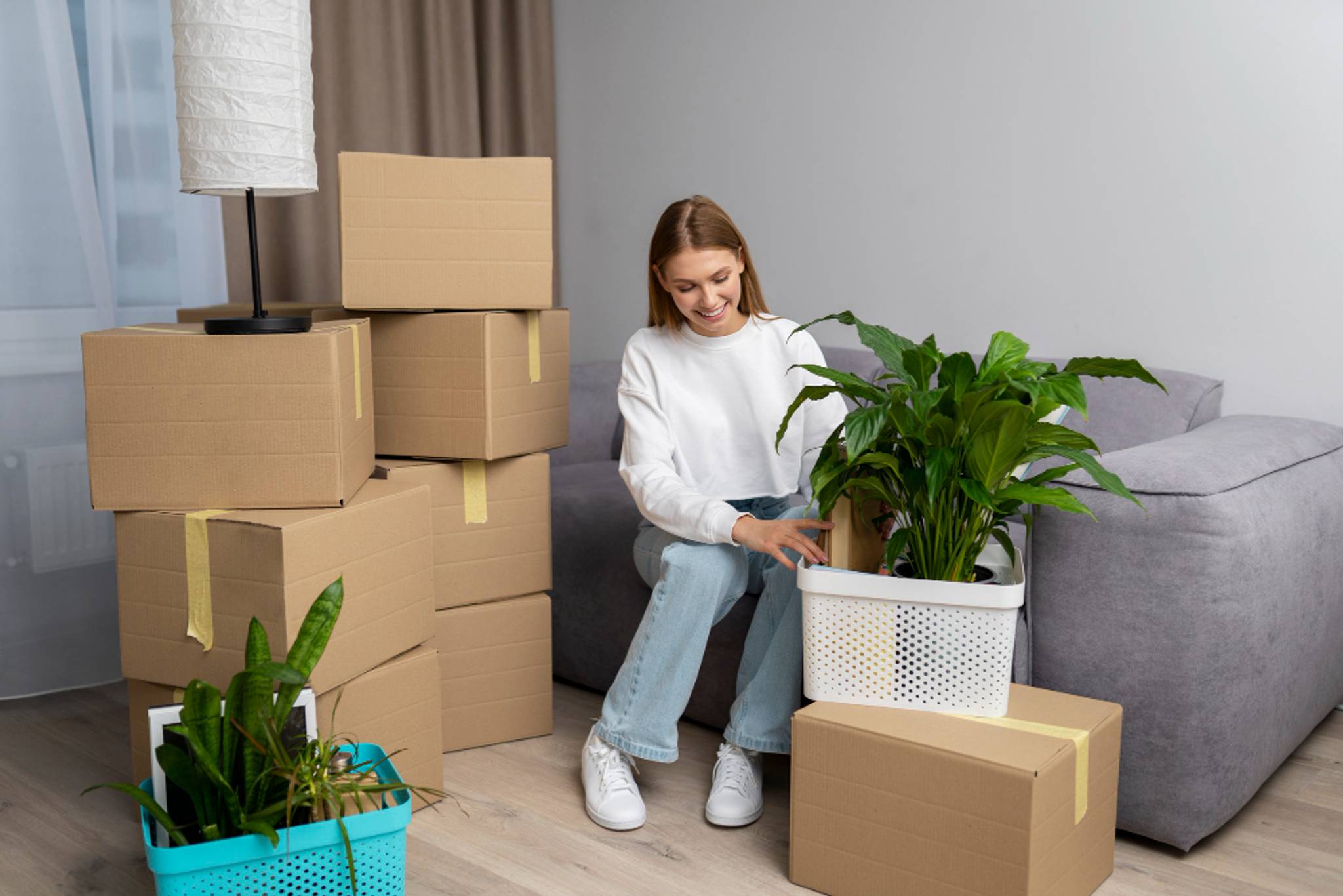 A person sat on a couch as she packs belongings into boxes