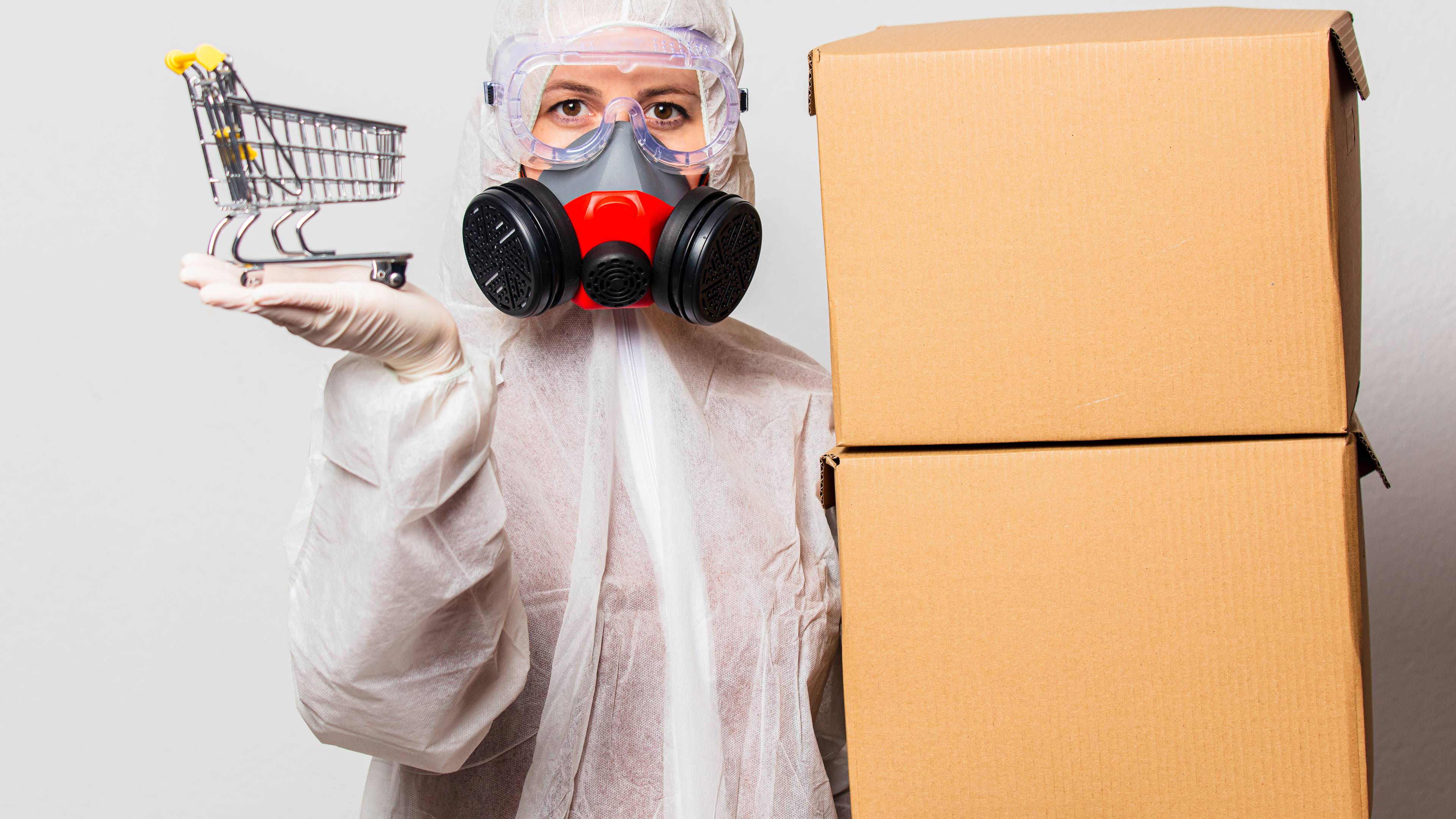 Person wearing a hazmat suit, carrying boxes