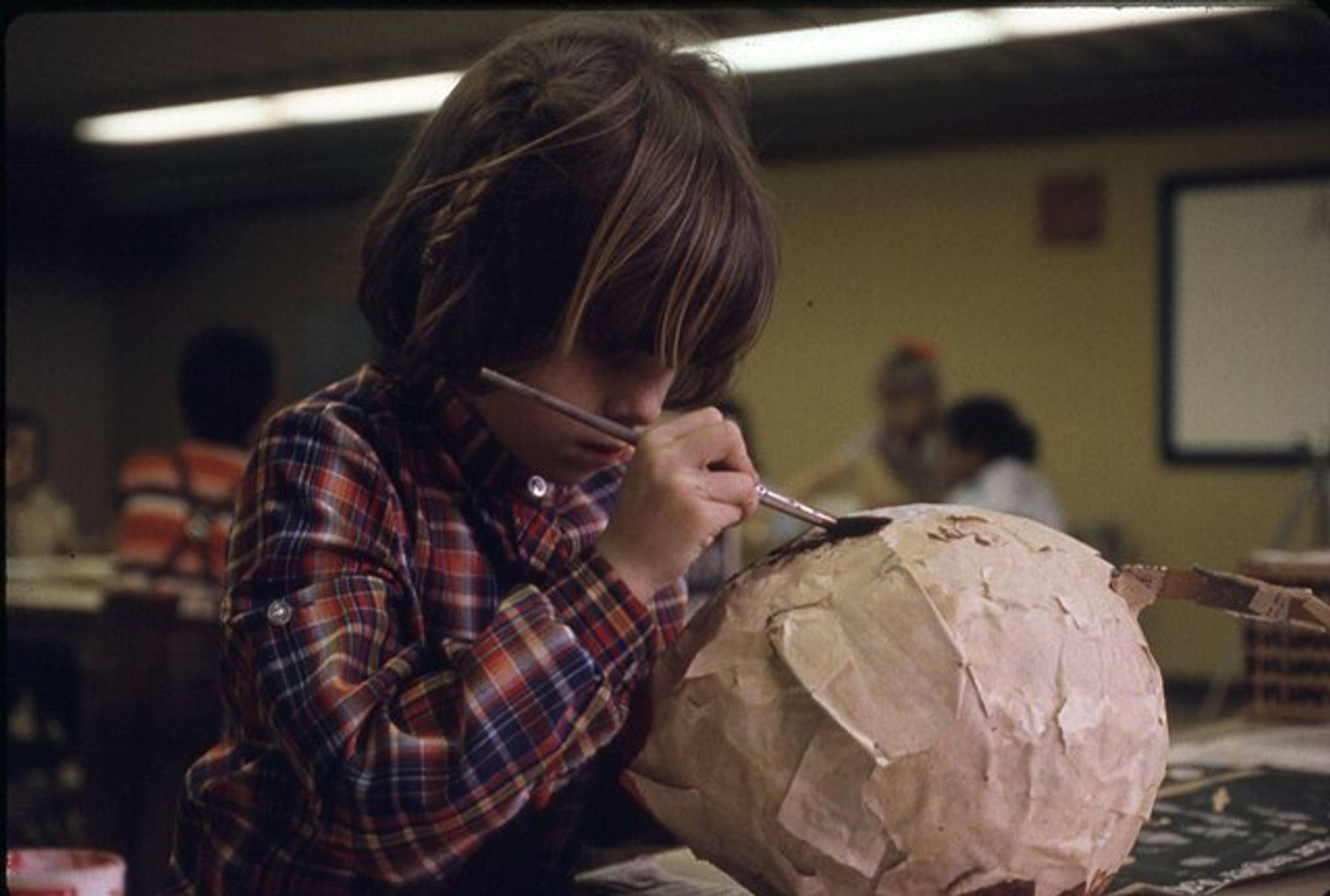 Child painting papier-mâché sculpture