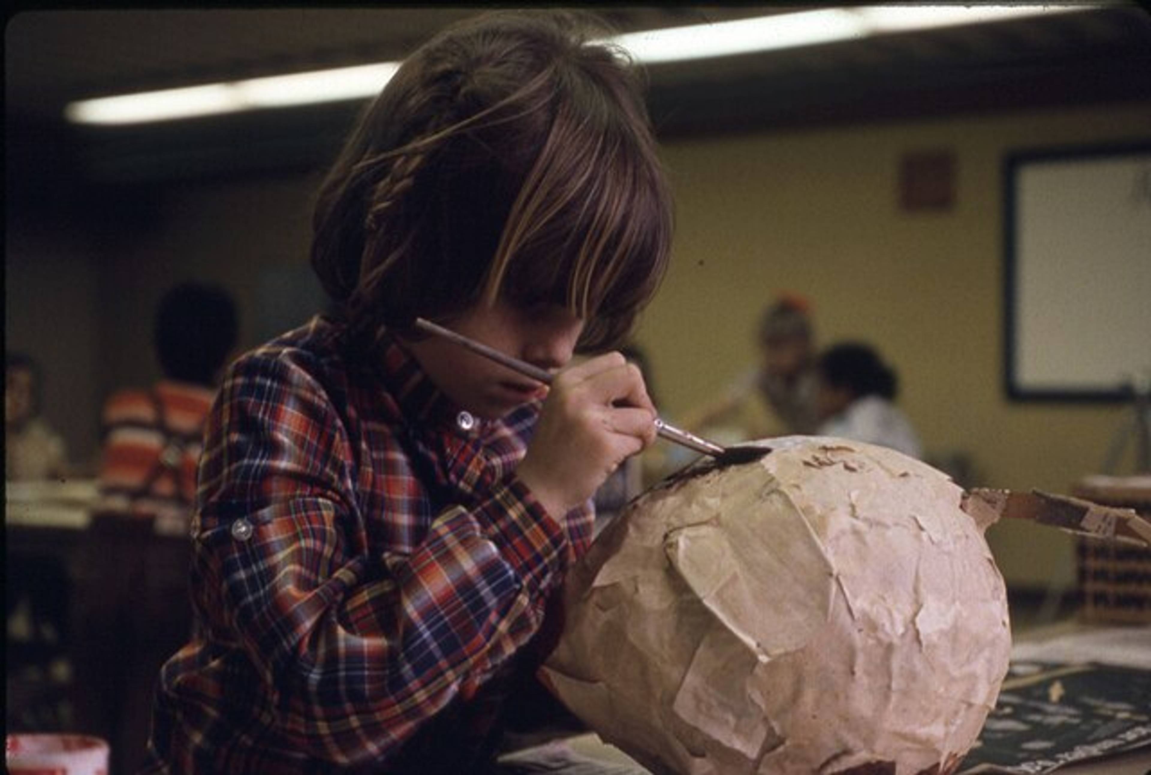 Child painting papier-mâché sculpture