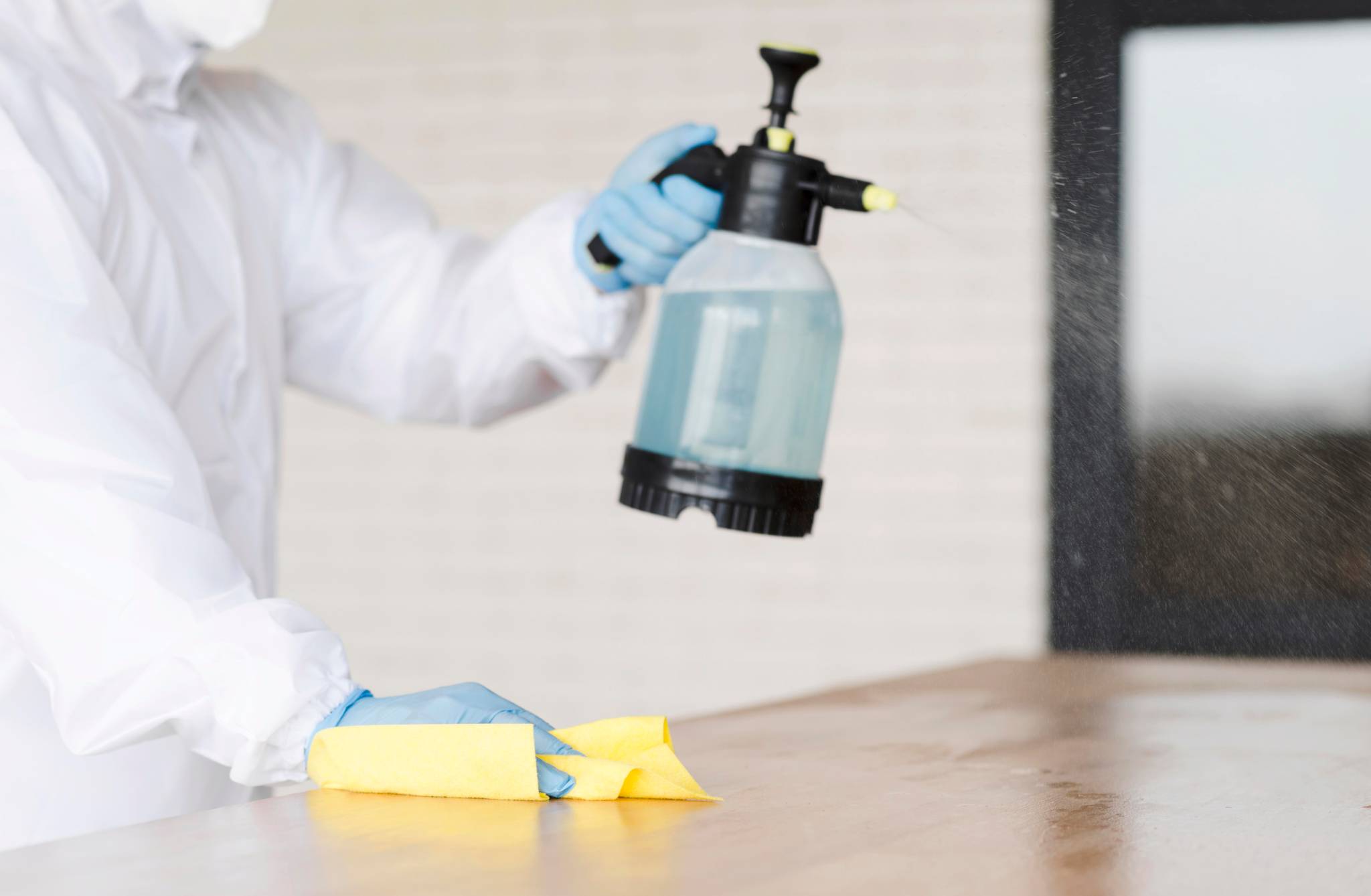 man holding disinfectant and wiping counter