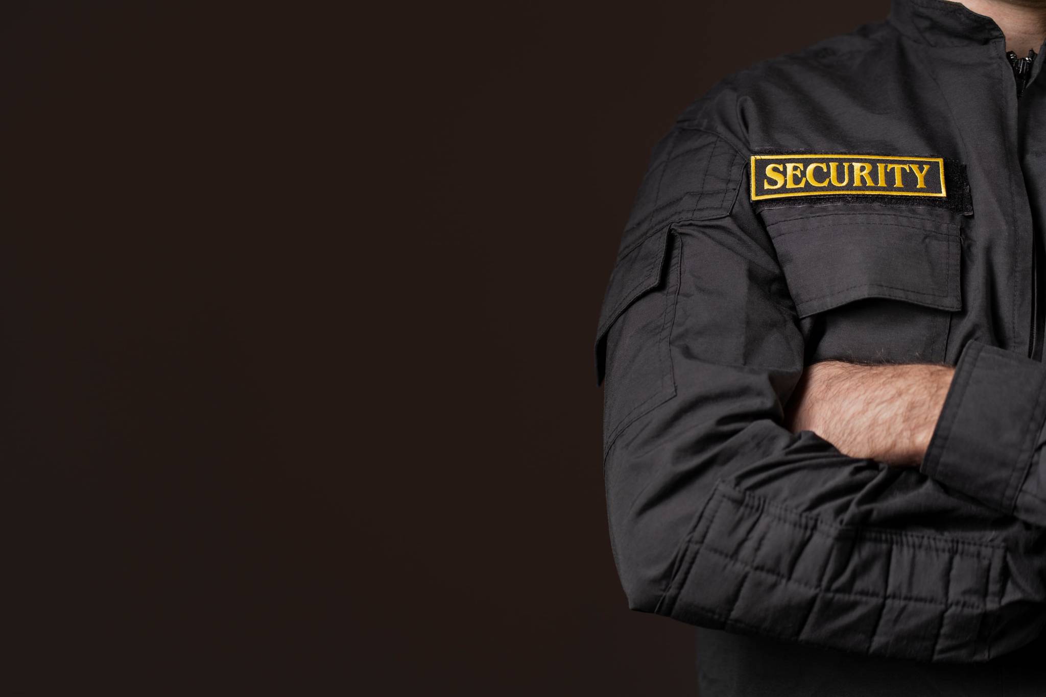Partial image of a man wearing security uniform.