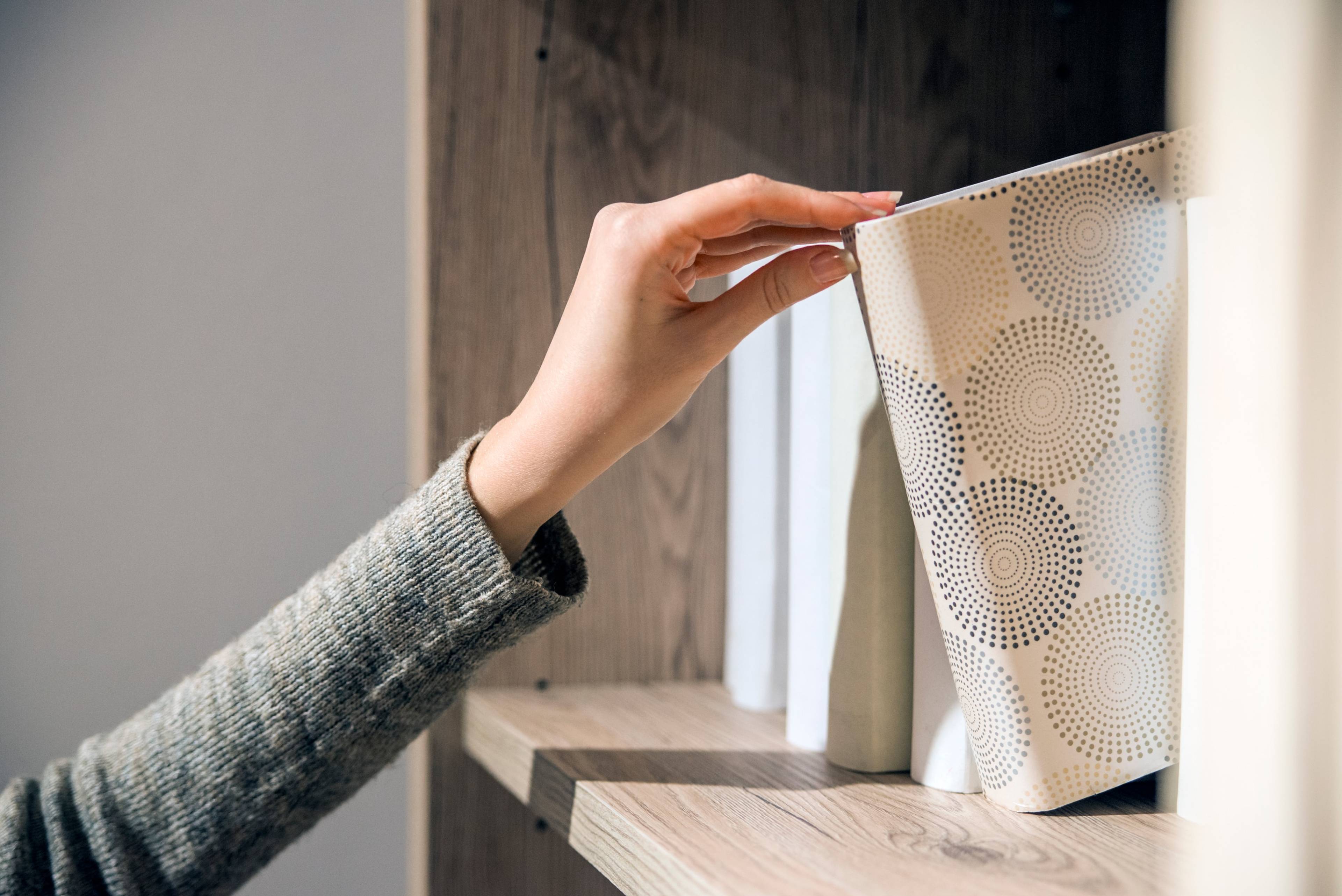 woman's hand retrieving book from shelves