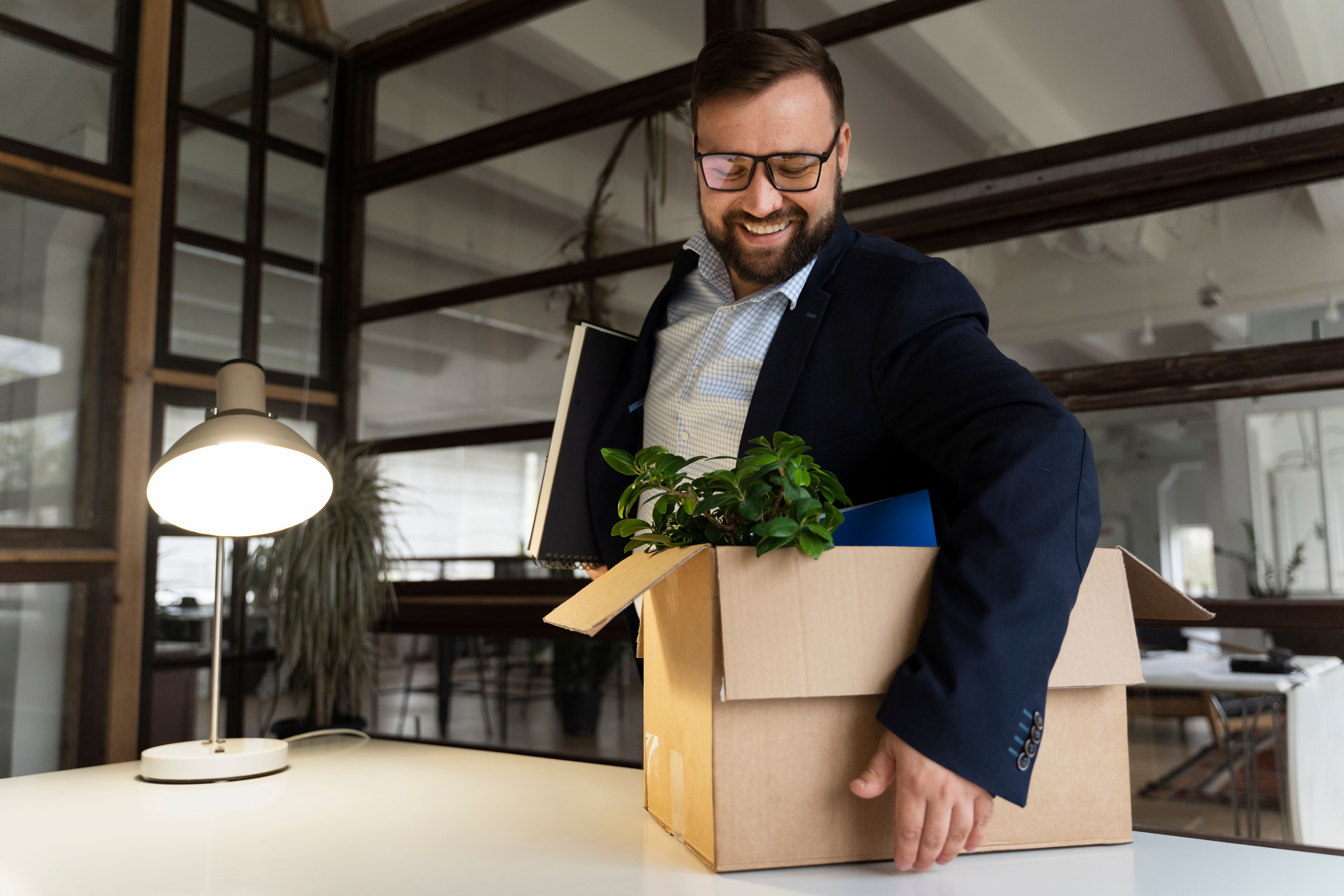 business man smiling picking up box with office stuff