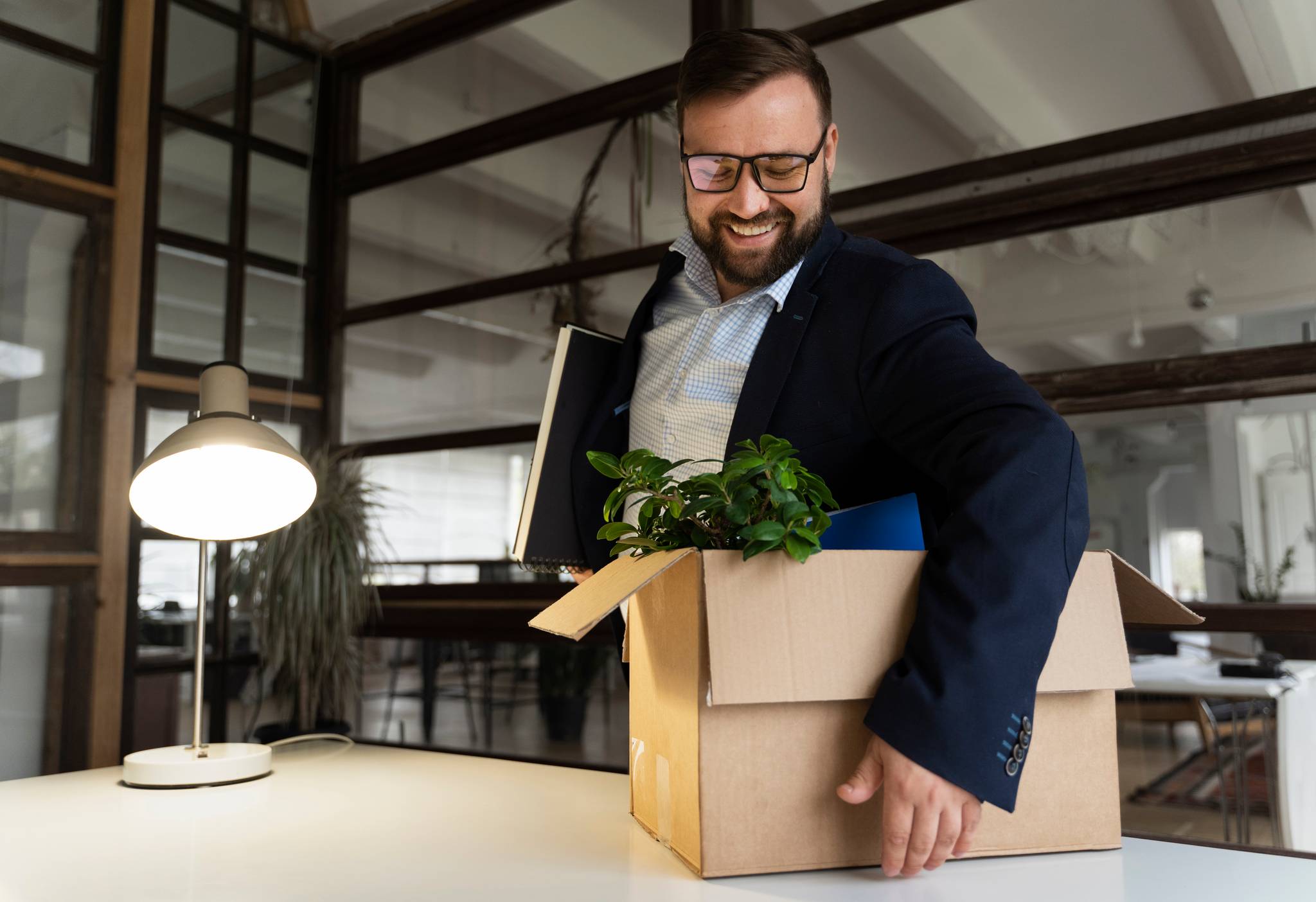 business man smiling picking up box with office stuff