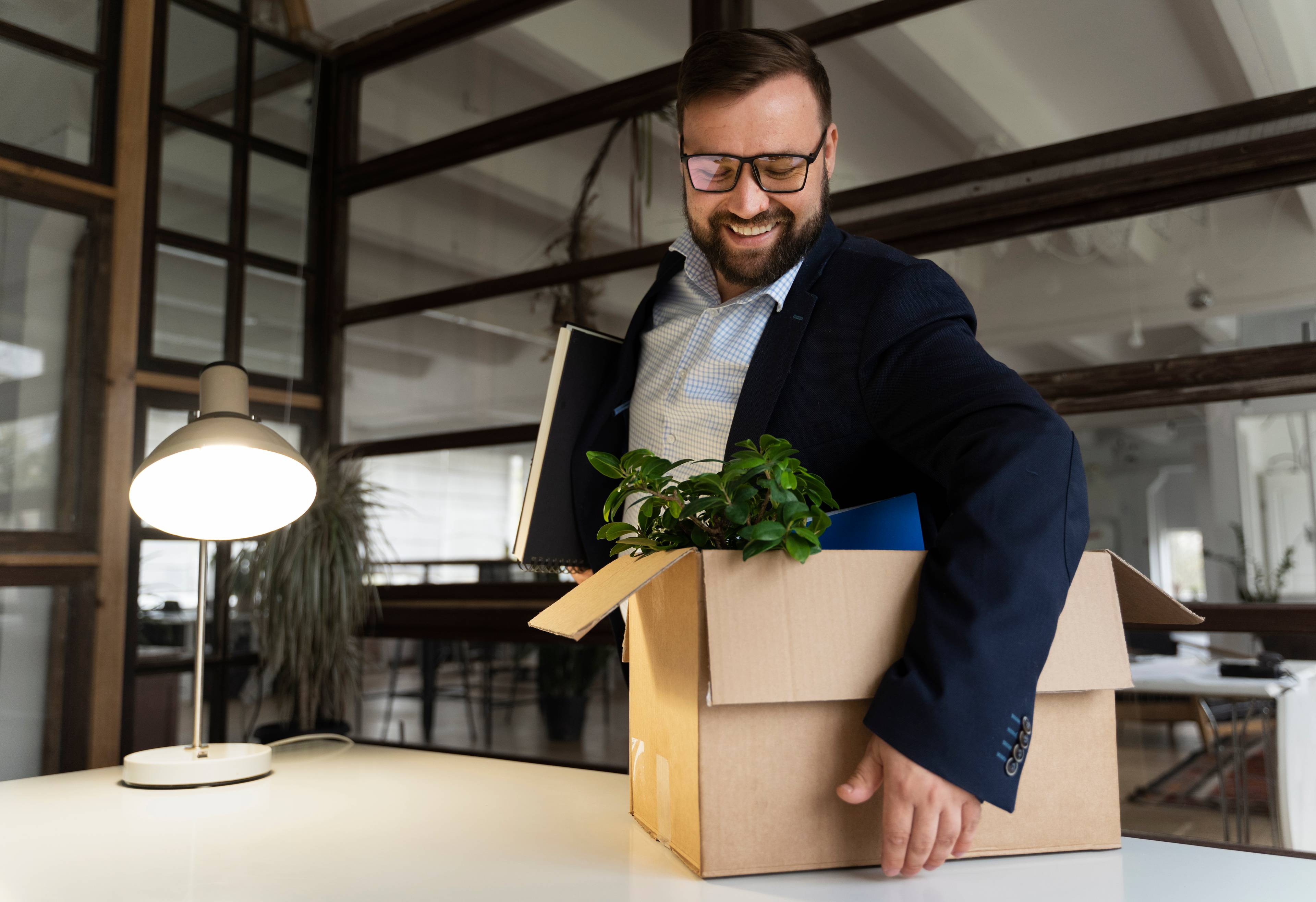 business man smiling picking up box with office stuff
