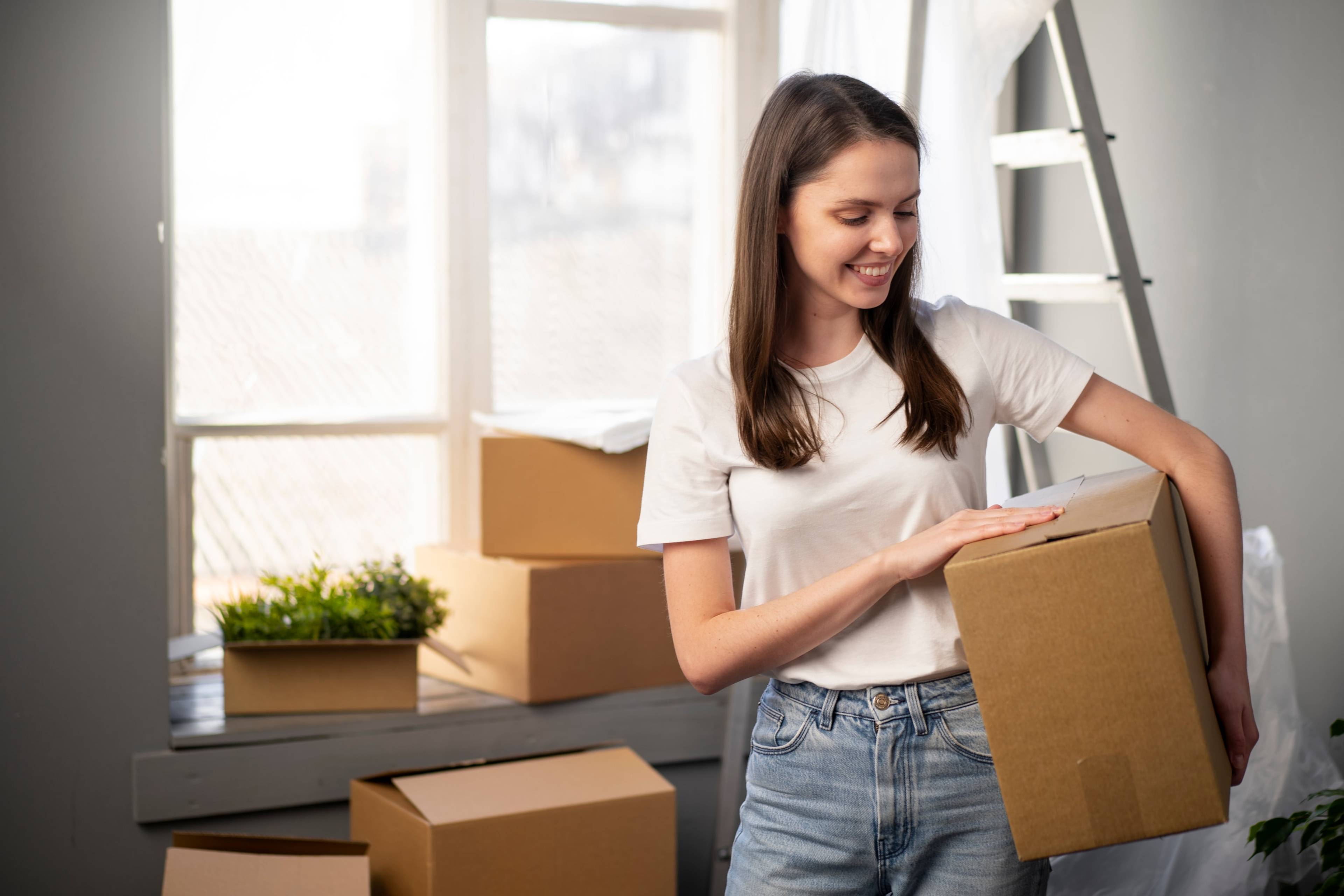 woman in apartment holding cardbaord box