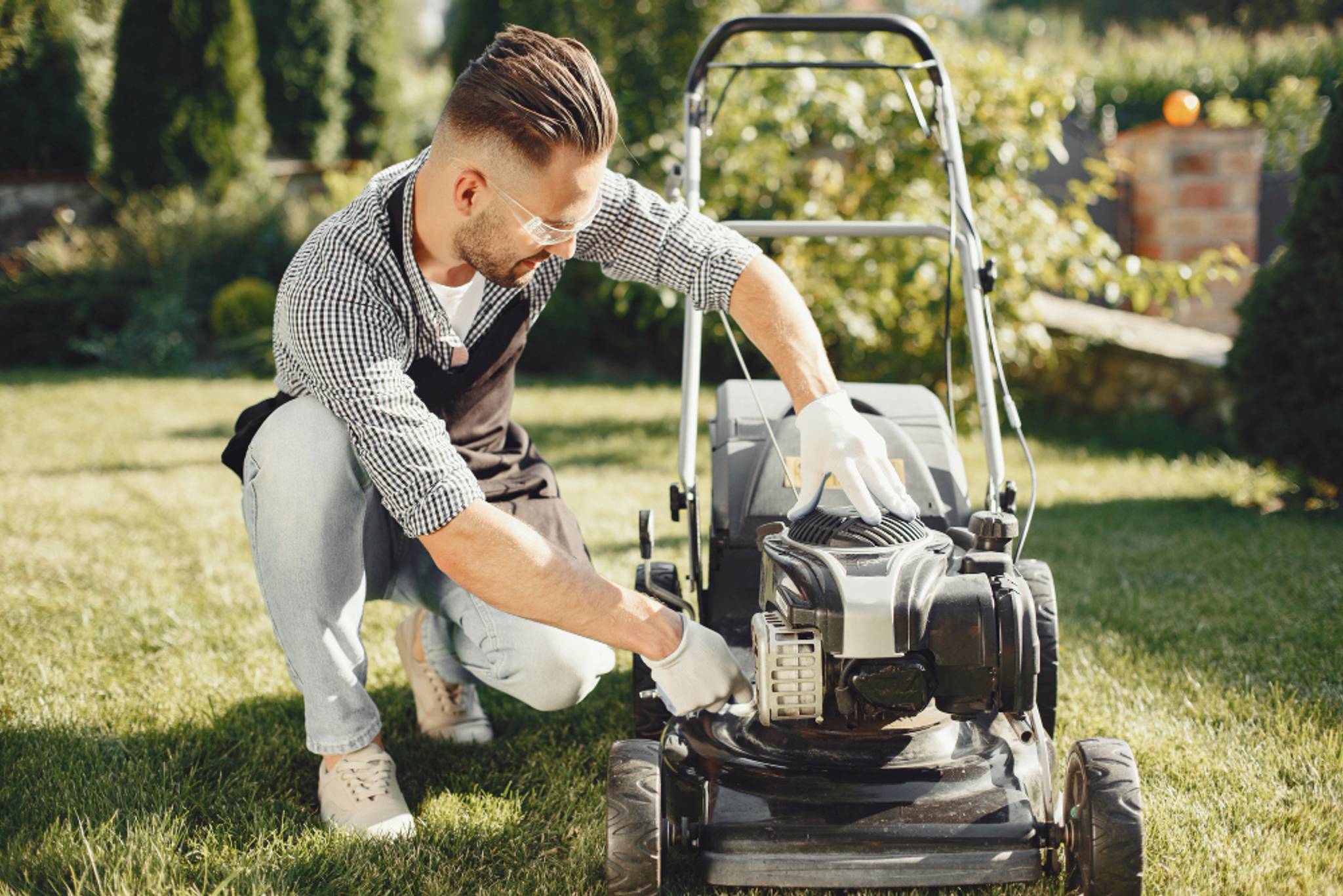 Someone checking their mower for any signs of damage whilst in their garden.