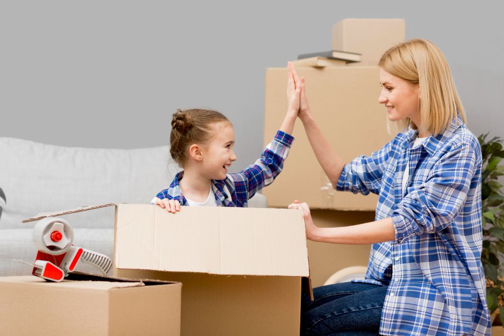 mum and young daughter hi five packing for house move