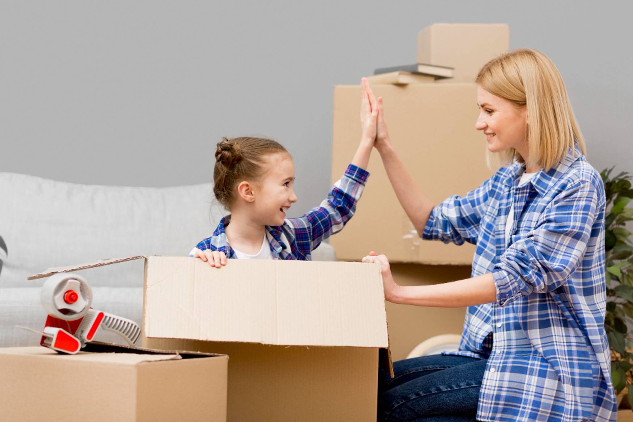 mum and young daughter hi five packing for house move