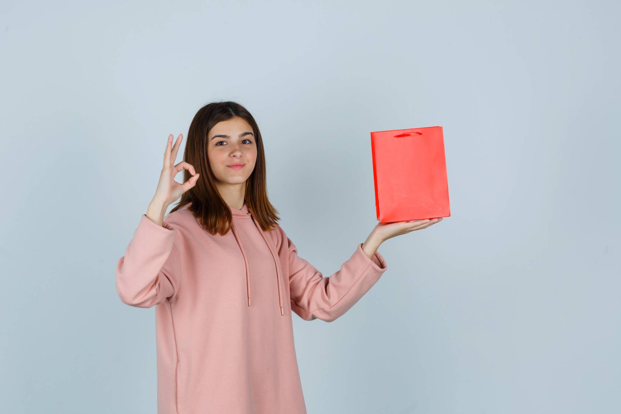 Young woman posing while holding out item
